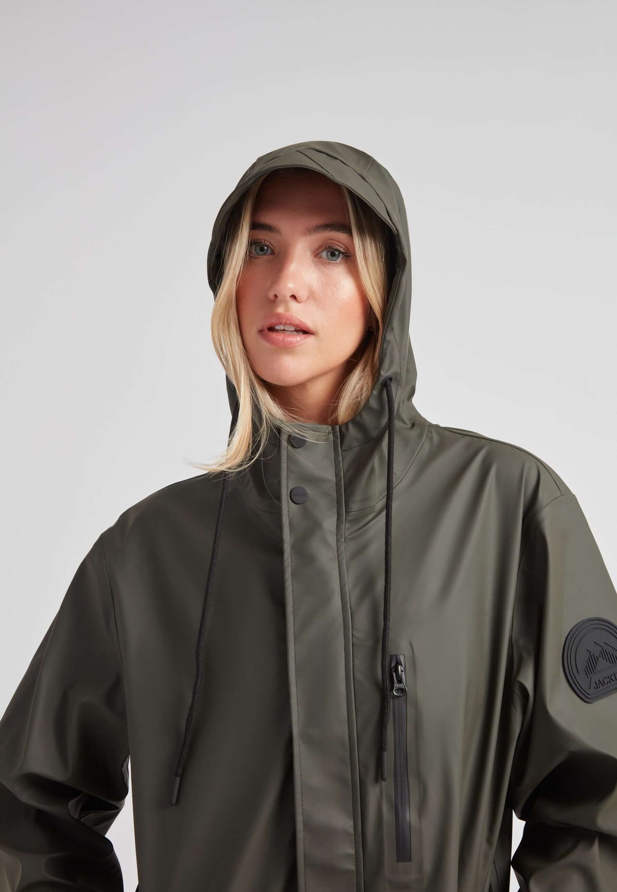 Elements unisex raincoat in khaki worn by a model with a hood, showcasing its lightweight design and style.