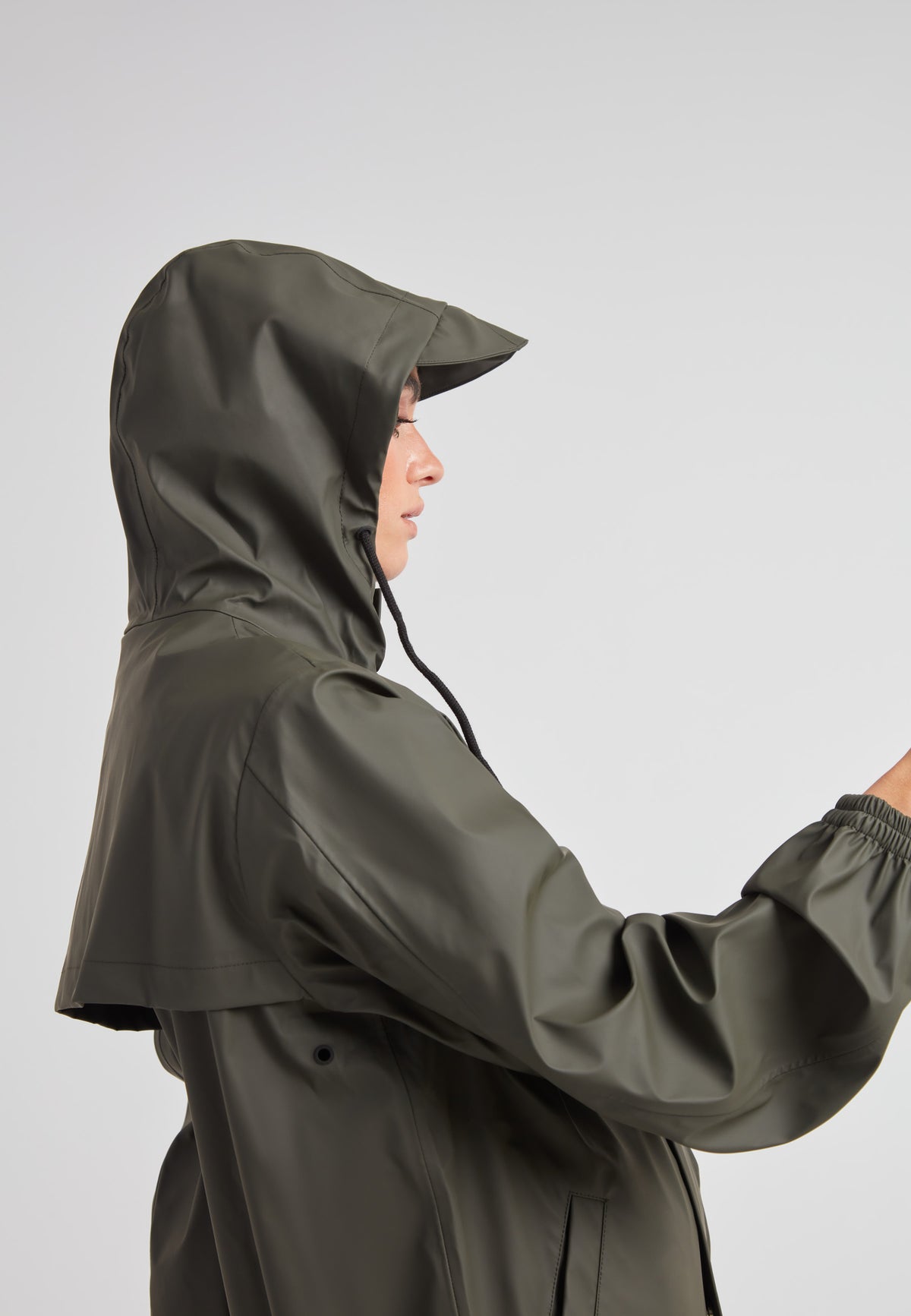 A model wearing the ELEMENTS Raincoat 2.0 Khaki featuring a hood and lightweight design.