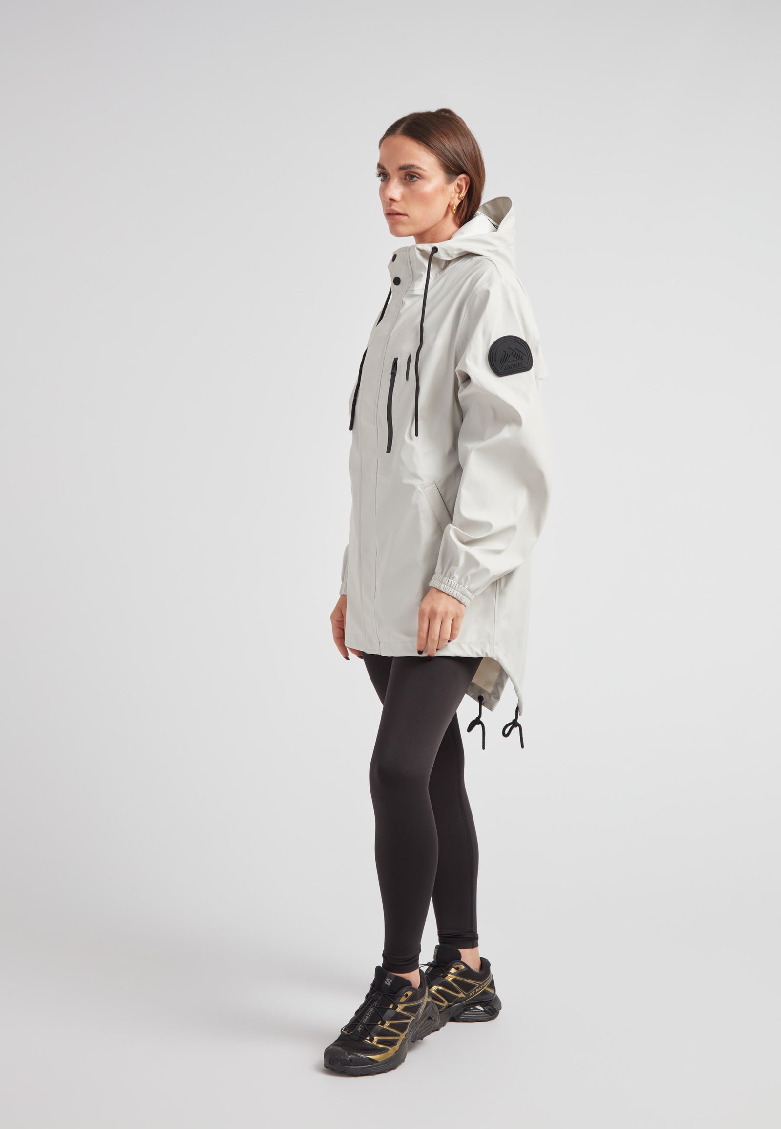 Woman wearing ELEMENTS Raincoat 2.0 Stone, showcasing lightweight weather protection and stylish design.