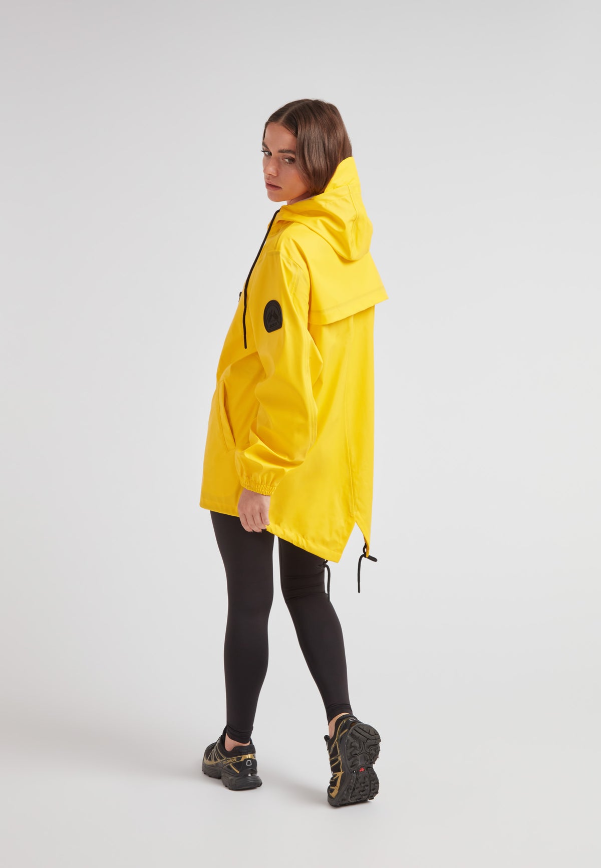 A model wearing the ELEMENTS Raincoat 2.0 Yellow, showcasing its lightweight design and hood.