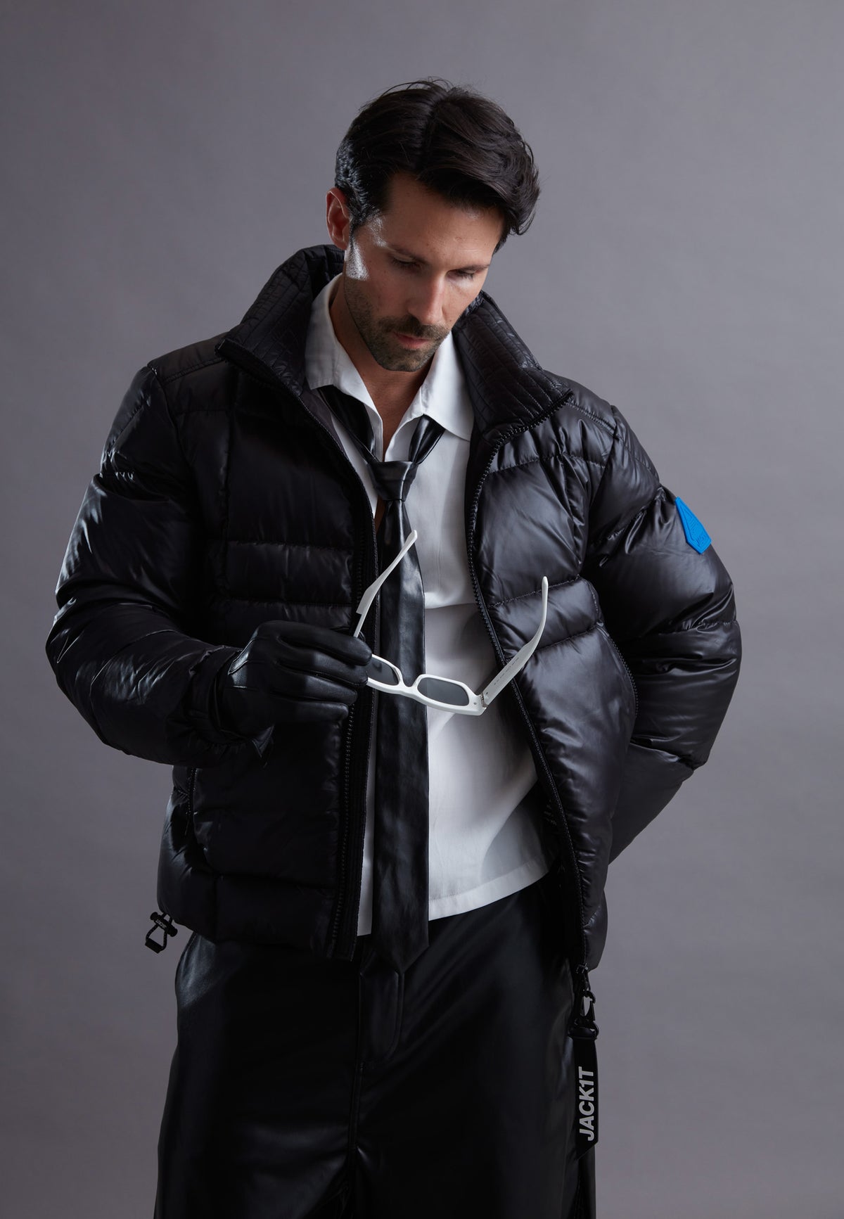 Man wearing a stylish black JACK1T jacket, adjusting sunglasses for a trendy look, perfect for cold weather.