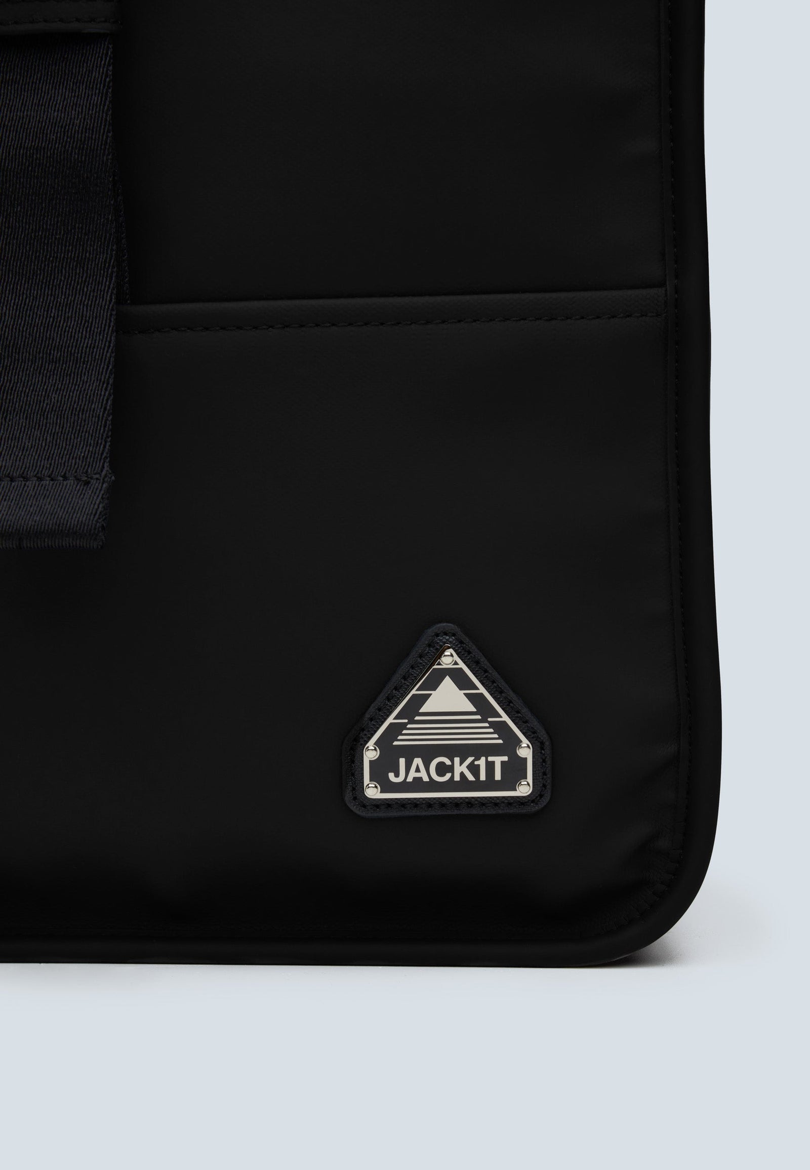 The JACK1T slim messenger laptop bag in black logo close-up on stylish fabric.