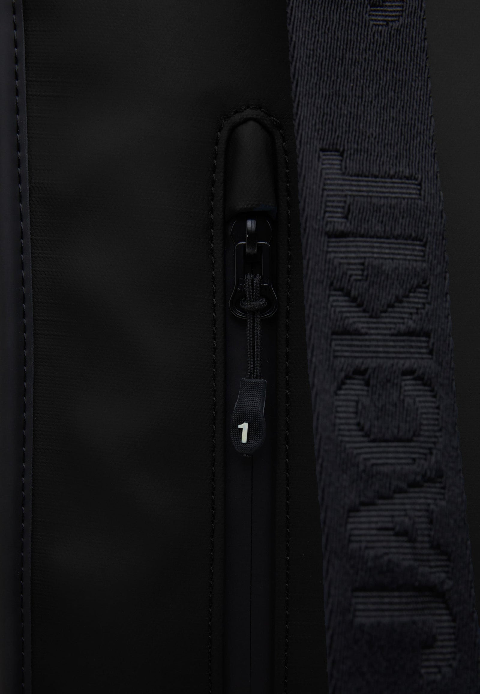 Close-up of The JACK1T slim messenger laptop bag in black showcasing zipper detail and brand logo.