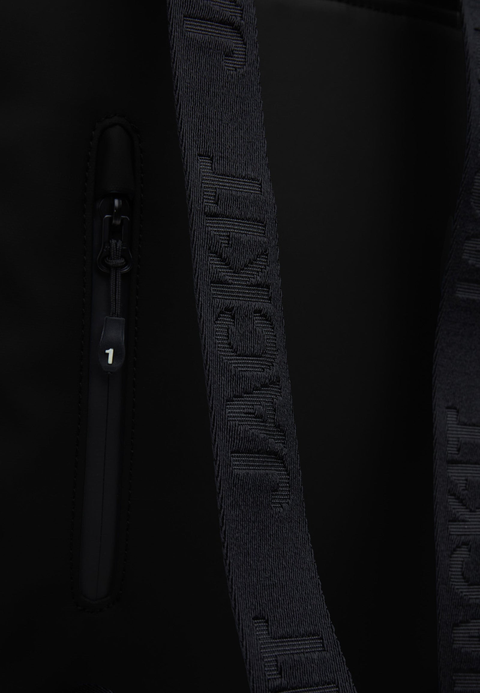 Close-up of The JACK1T slim messenger laptop bag in black showing the strap and zip detail.