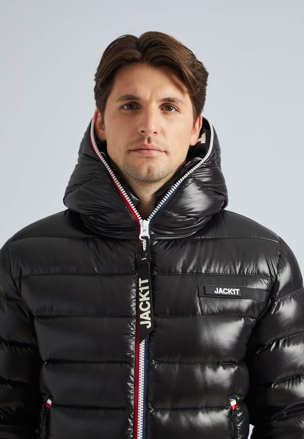 Man wearing a black puffer jacket with a stylish hood and zippers, showcasing the R3D Tricolore design.