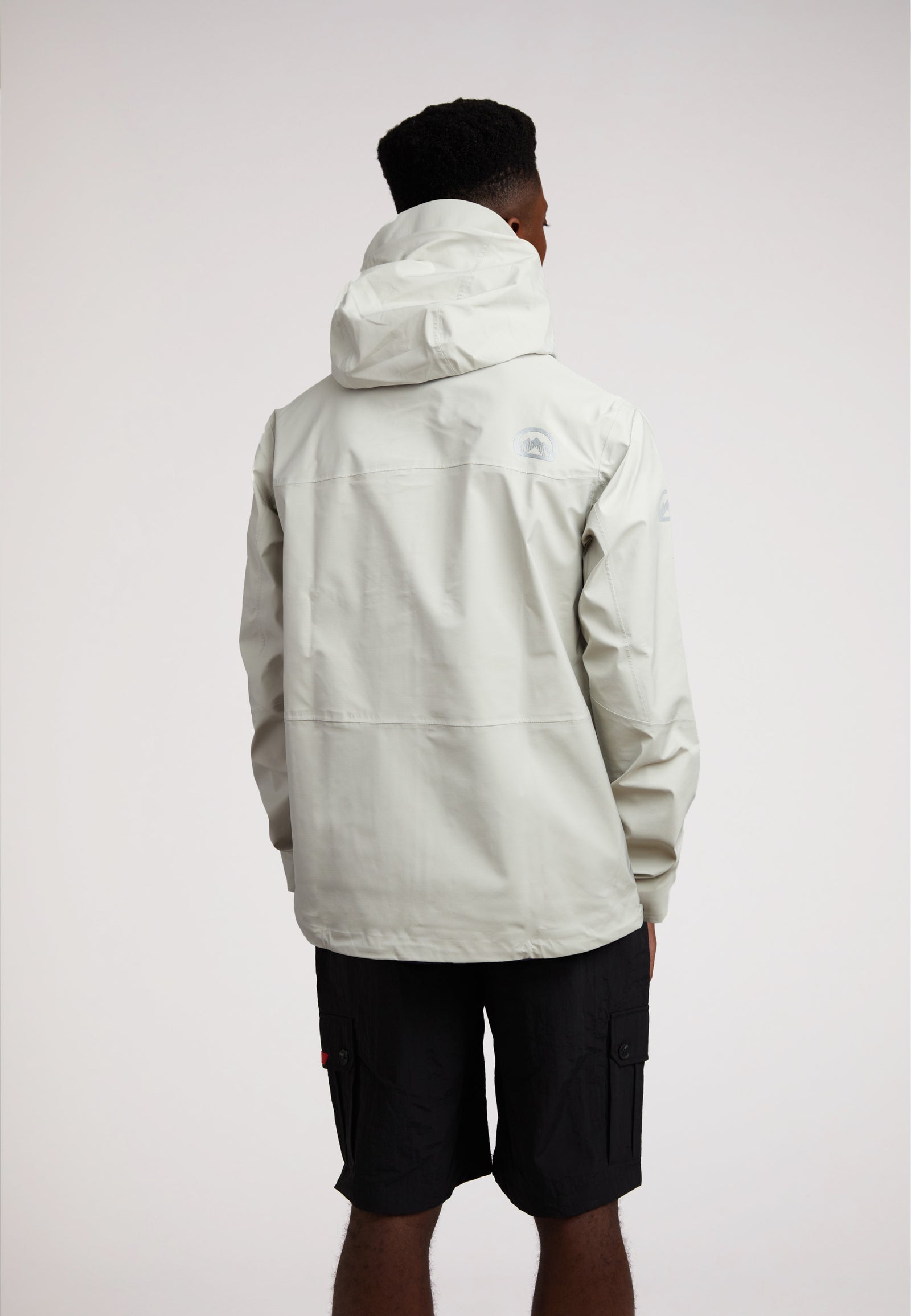 Man wearing the Stone mens lithium waterproof jacket, showcasing its back design and hood.