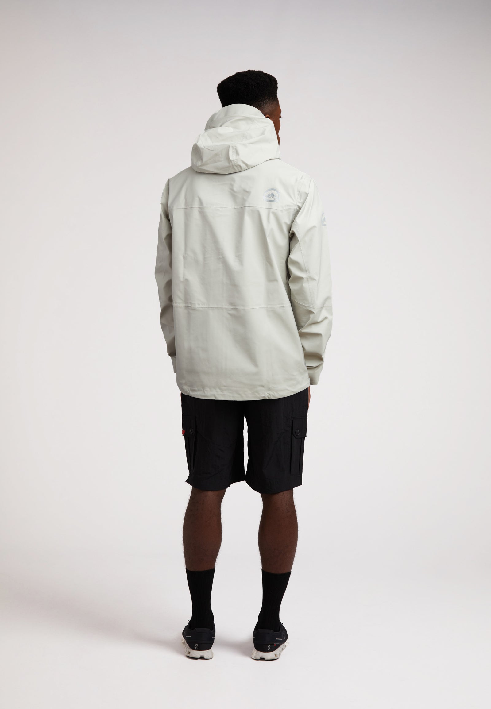 Stone mens lithium waterproof jacket worn by a man from the back, showcasing its design and materials in a neutral setting.