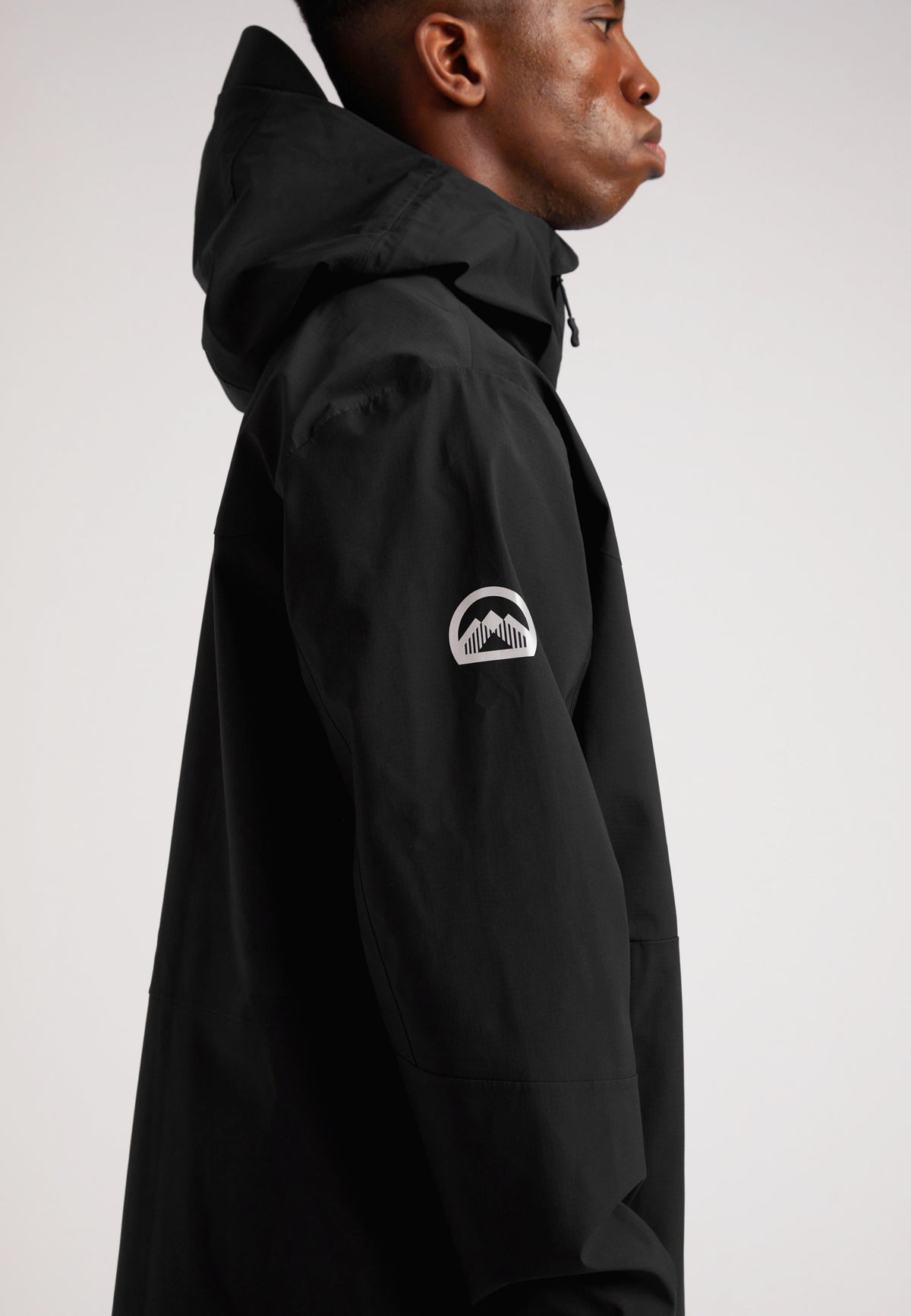 Black mens Lithium waterproof jacket showcased on a model in profile view, highlighting its hood and durable design.