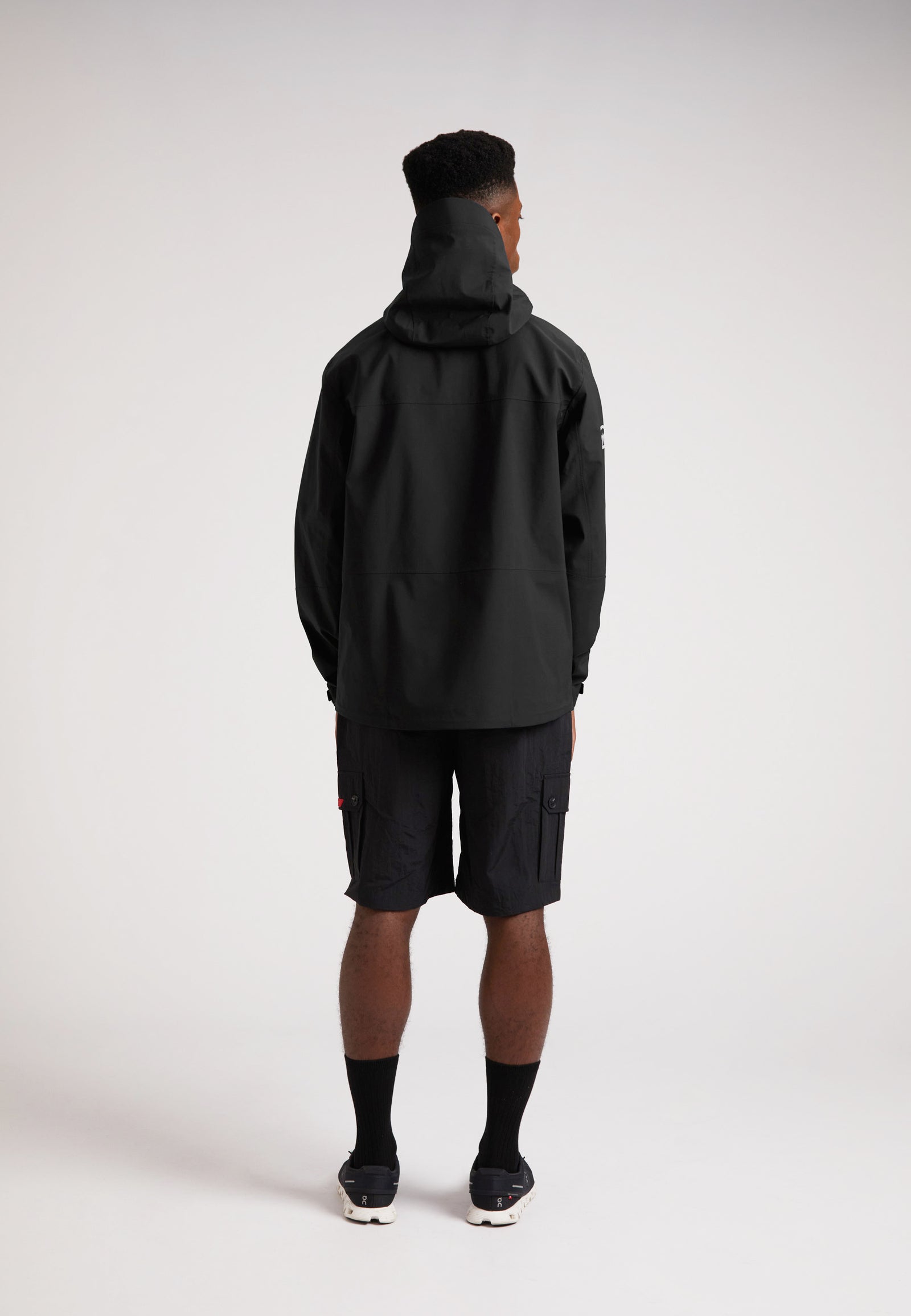 Black mens Lithium waterproof jacket on model from the back, showcasing the hoodie and durable design.