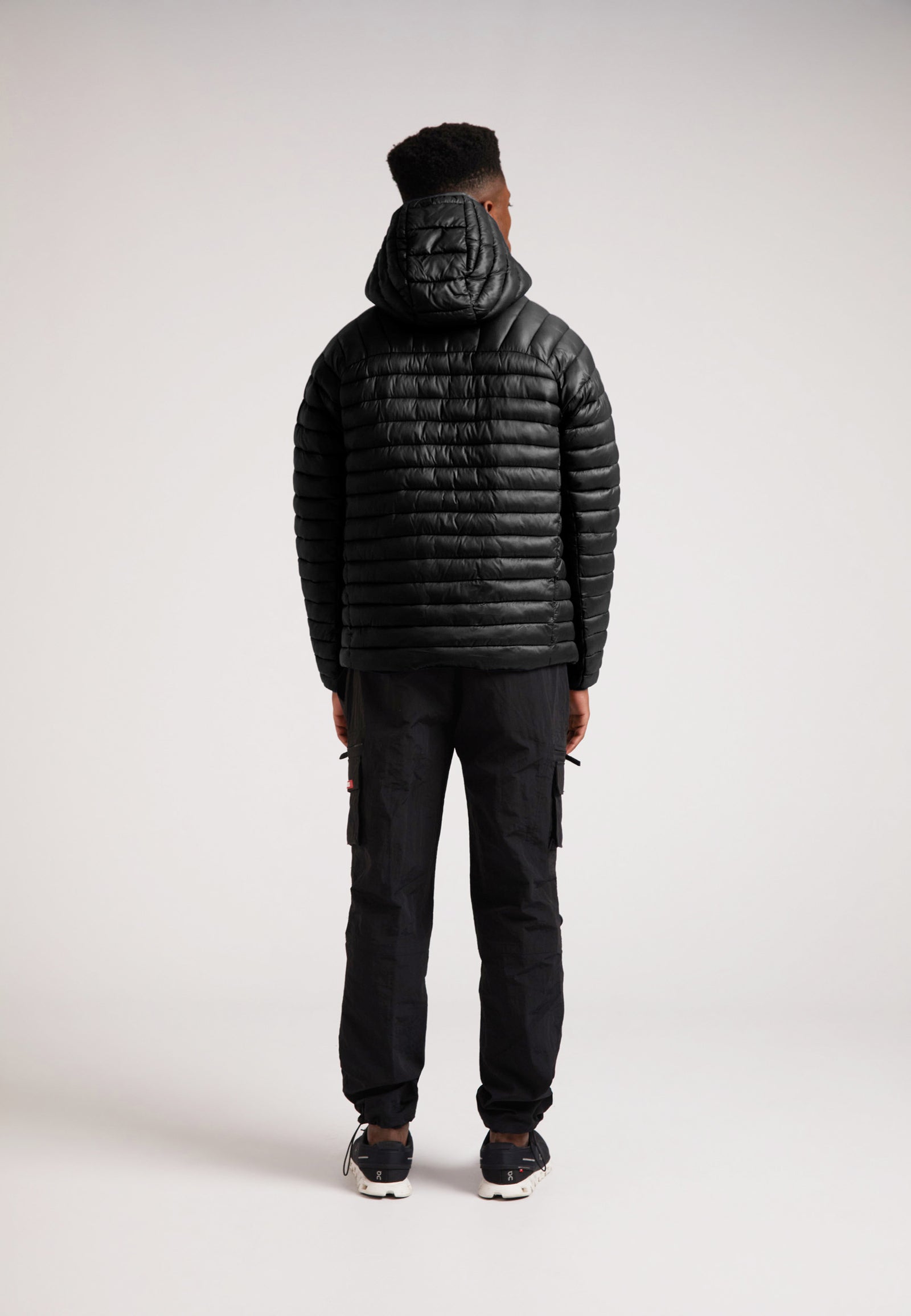 Model wearing SATEL1TE Hooded Jacket 2.0 Black from the back, showcasing its sleek design and hood.