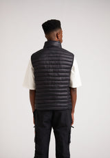Back view of a model wearing the SATEL1TE Lightweight Puffer Gilet 2.0 Black, showcasing its sleek design.