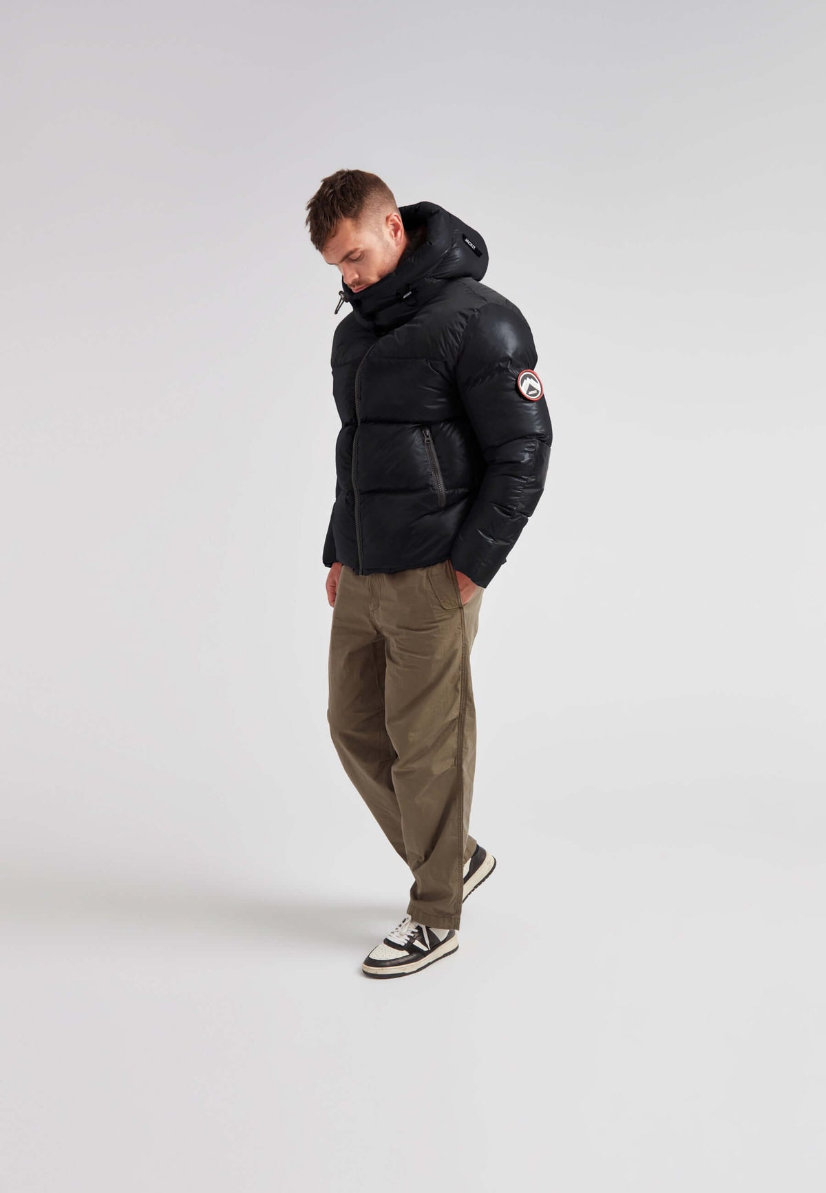 Man wearing Expedition Parka Puffer Men Black jacket with oversized hood and boxy silhouette.