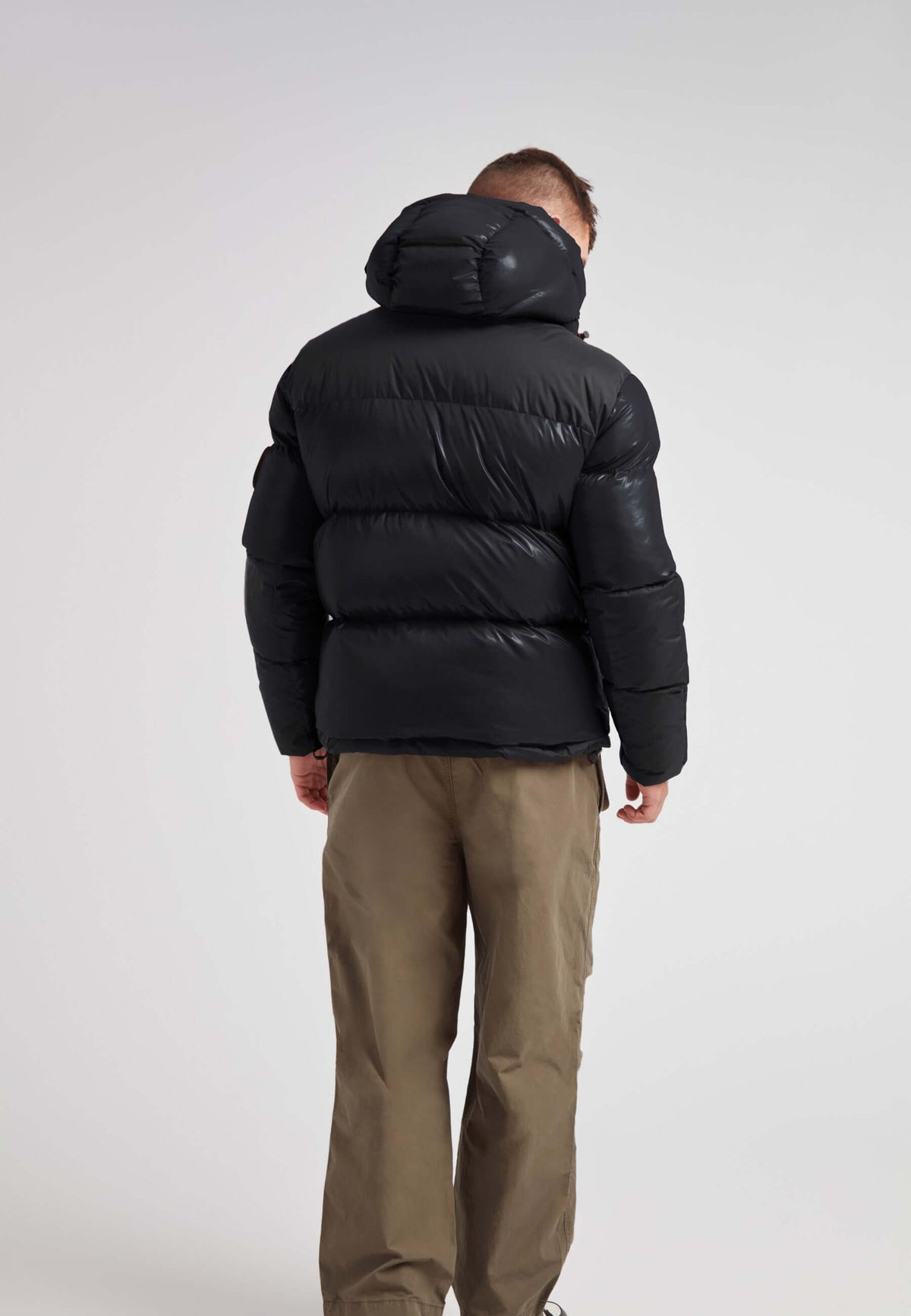 Back view of a man wearing an Expedition Parka Puffer Men Black jacket, showcasing its stylish, oversized hood and puffer design.