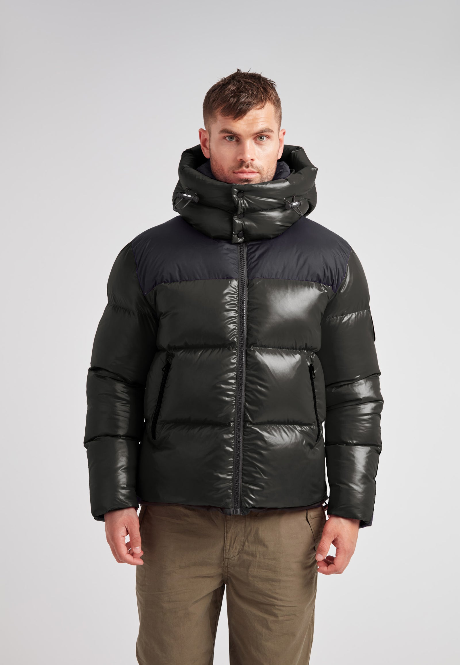 Expedition Parka Puffer Men Emerald model wearing a black and green puffer jacket with a large hood.