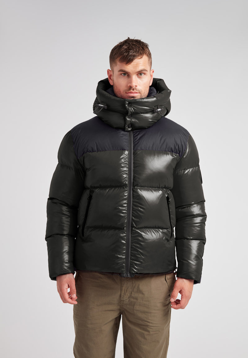 Expedition Parka Puffer Men Emerald model wearing a black and green puffer jacket with a large hood.
