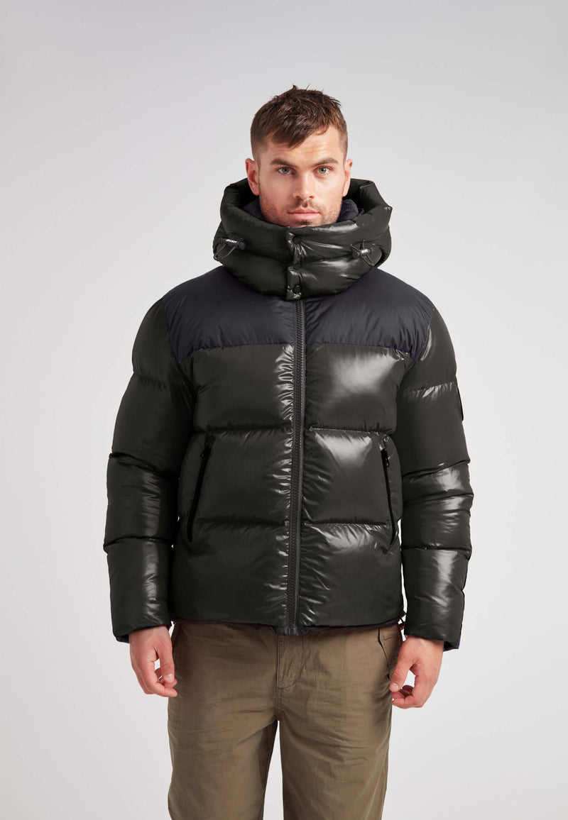 Expedition Parka Puffer Men Emerald model wearing a black and green puffer jacket with a large hood.