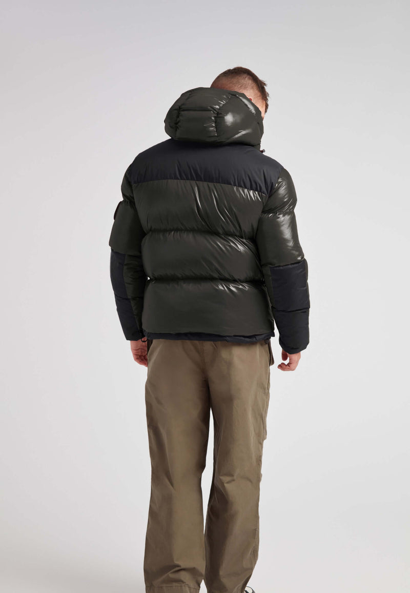 Back view of a man wearing the Expedition Parka Puffer Men Emerald jacket showcasing its bold color block design.