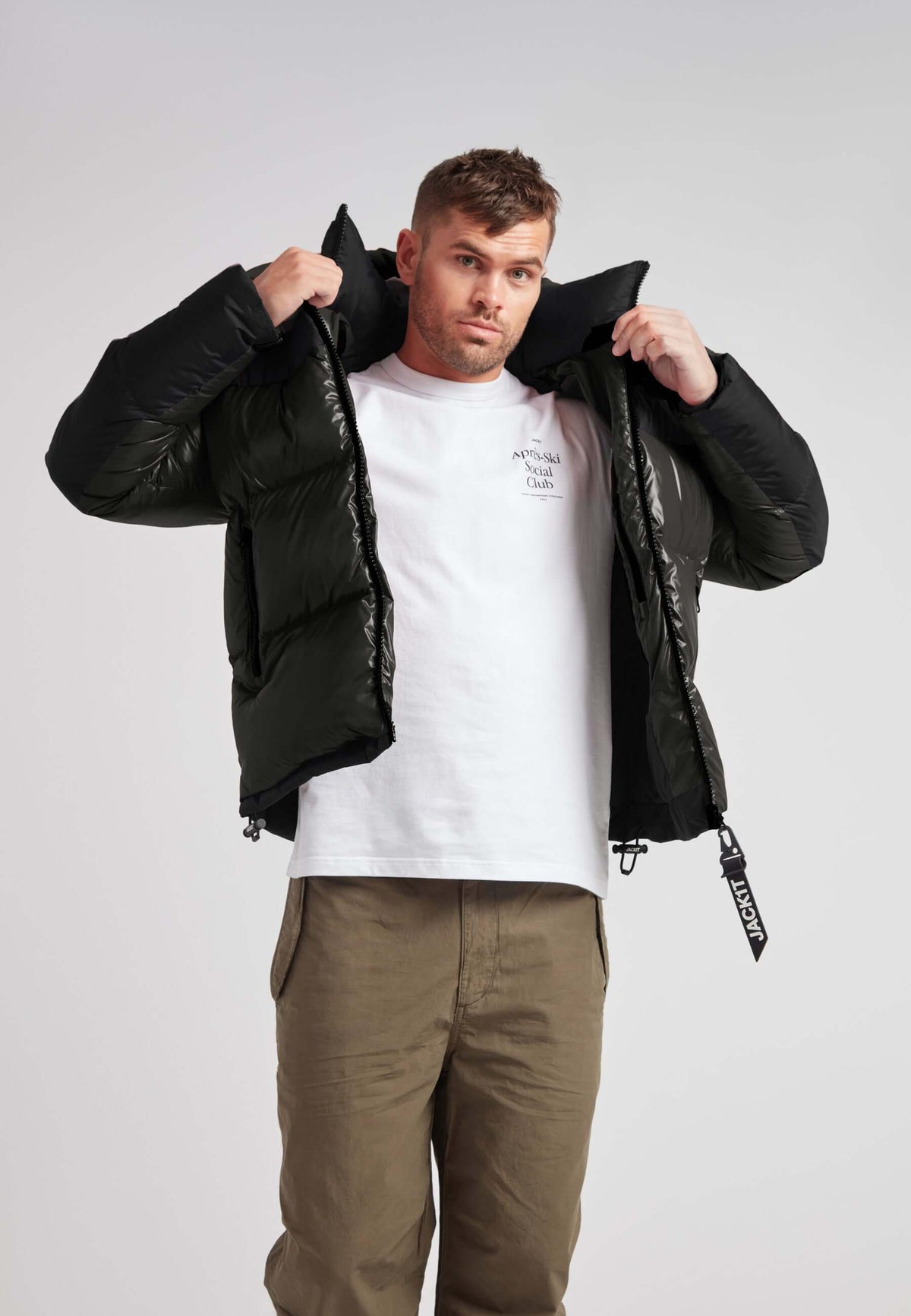Man wearing Expedition Parka Puffer Men Emerald jacket adjusting the hood for warmth.