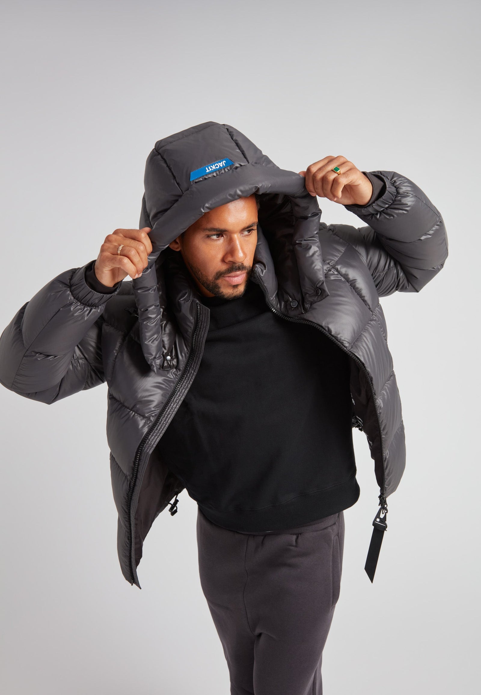 Man wearing the EZ Boxed Puffer Racer Jacket Lux Graphite with the hood up, showcasing its sleek design and winter-ready features.