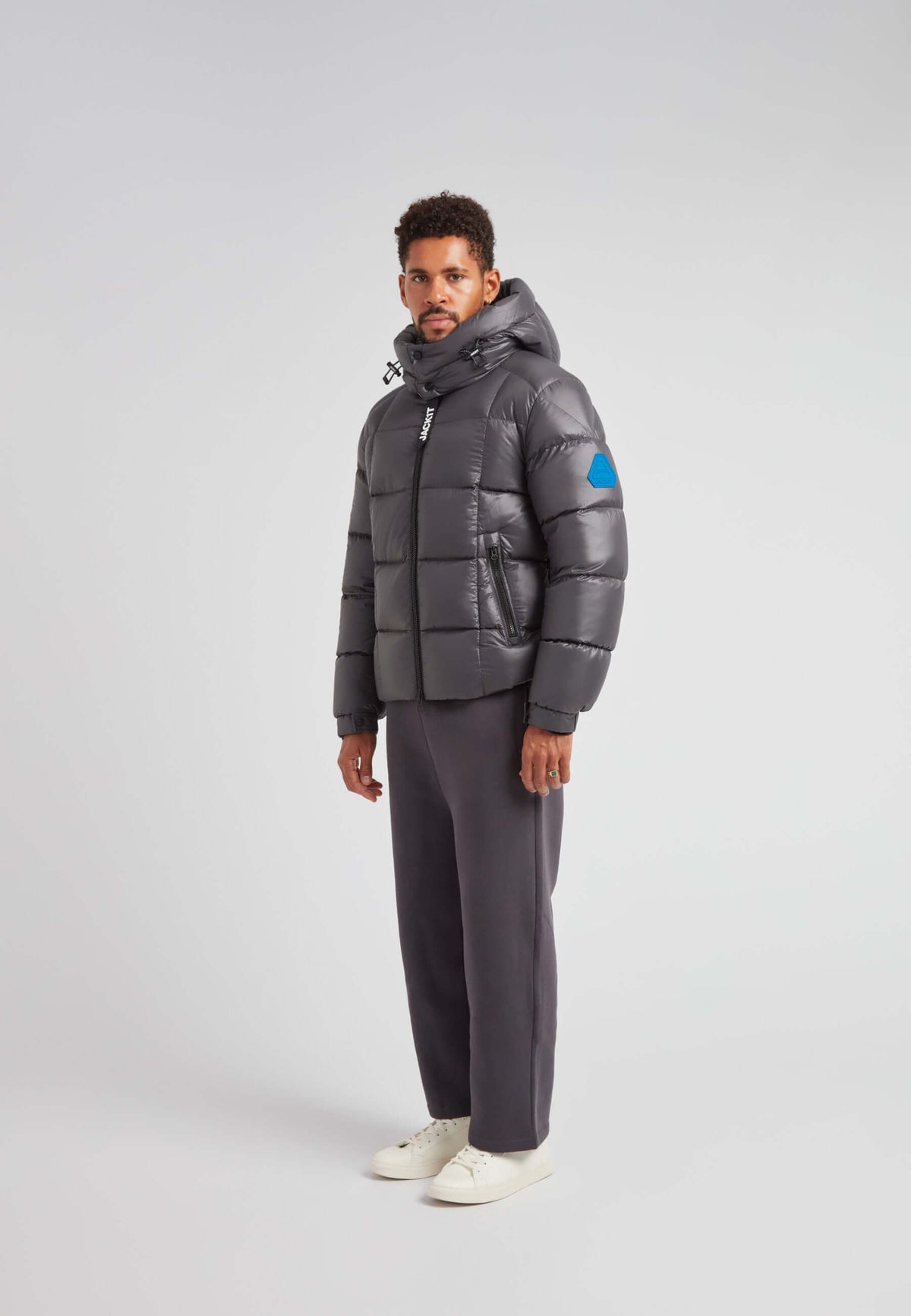 Model wearing EZ Boxed Puffer Racer Jacket Lux Graphite with hood and puffer design in a studio setting.