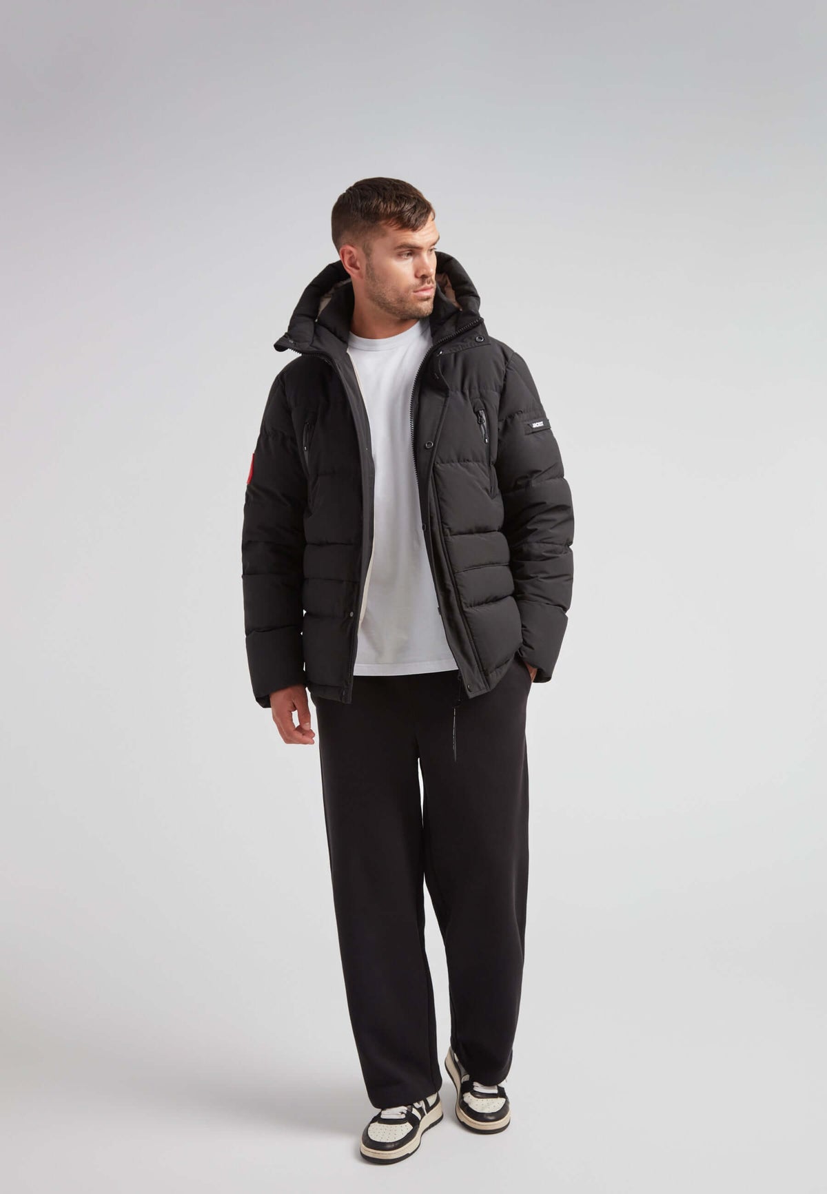 Man wearing EZ Frontier Prime Down Puffer Jacket Matt Black with casual style, showcasing urban winter fashion.