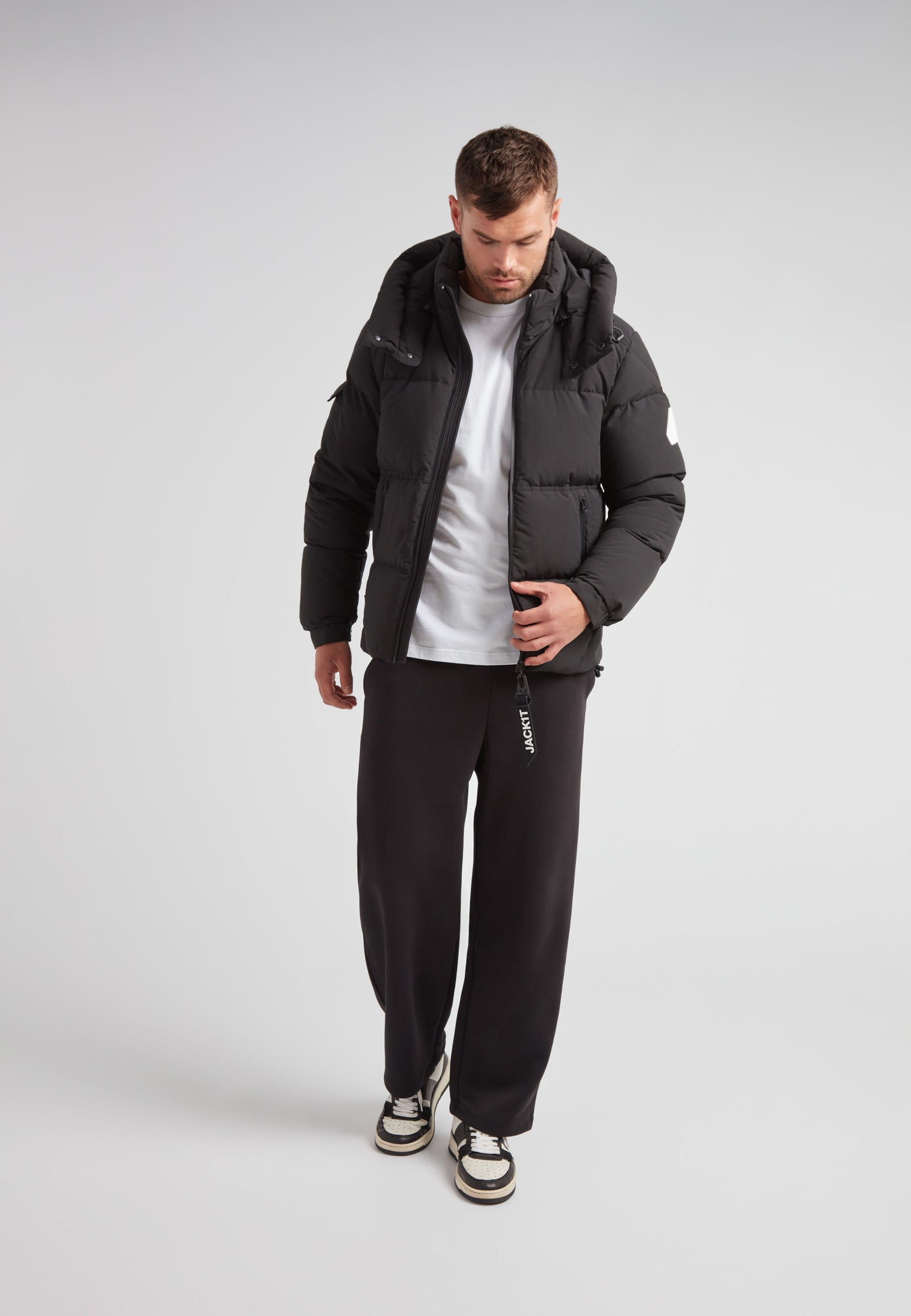 Model wearing EZ Water Puffer Racer Jacket Matt Black with casual outfit in studio setting.