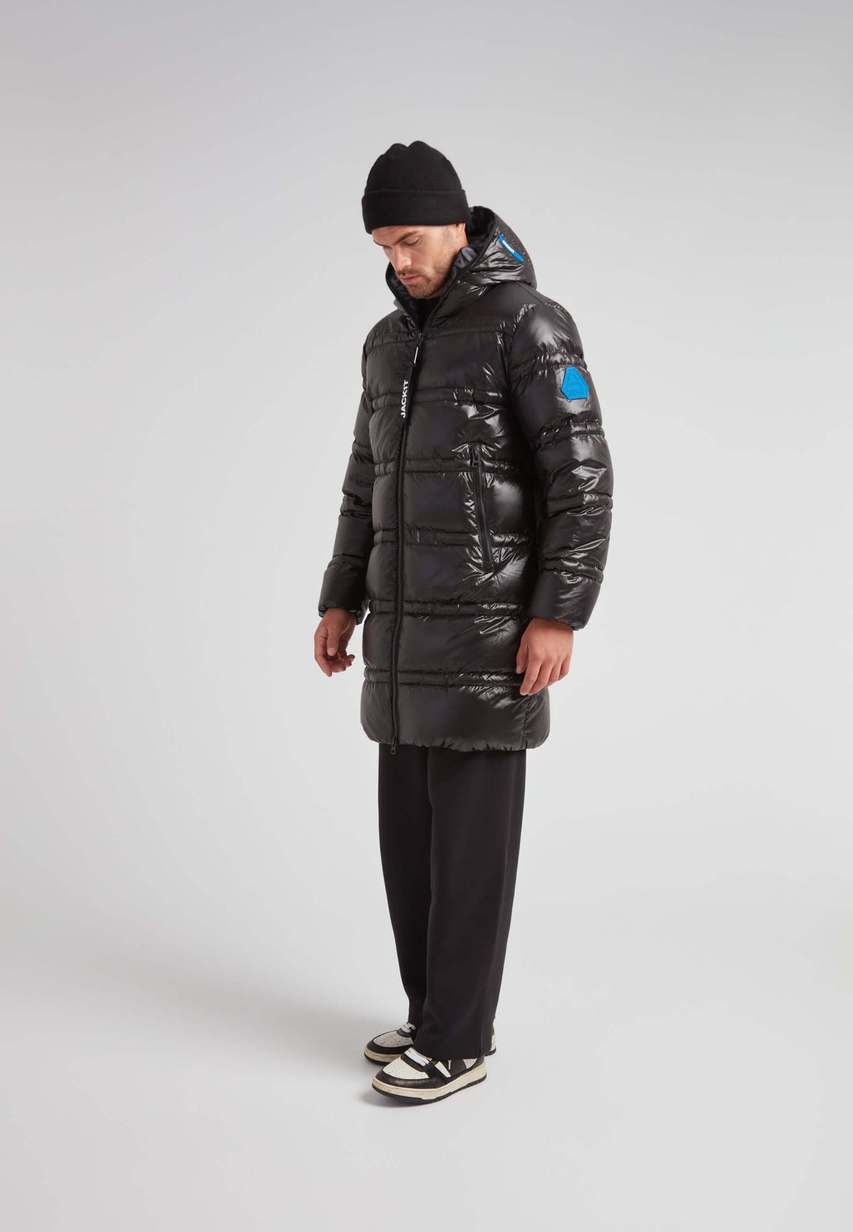 R4D Tramline Puffer Coat Lux Black worn by a man standing in profile, showcasing its longline design and insulation.
