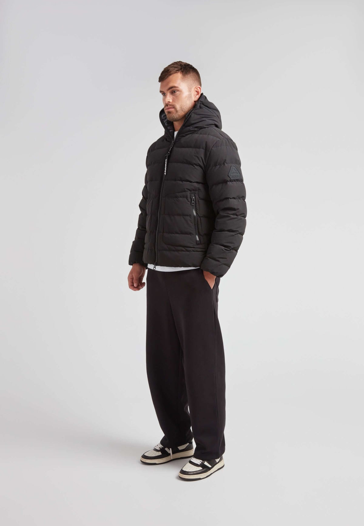 R4D Tramline Puffer Racer Jacket Matt Black worn by man standing, showcasing modern style and warmth.