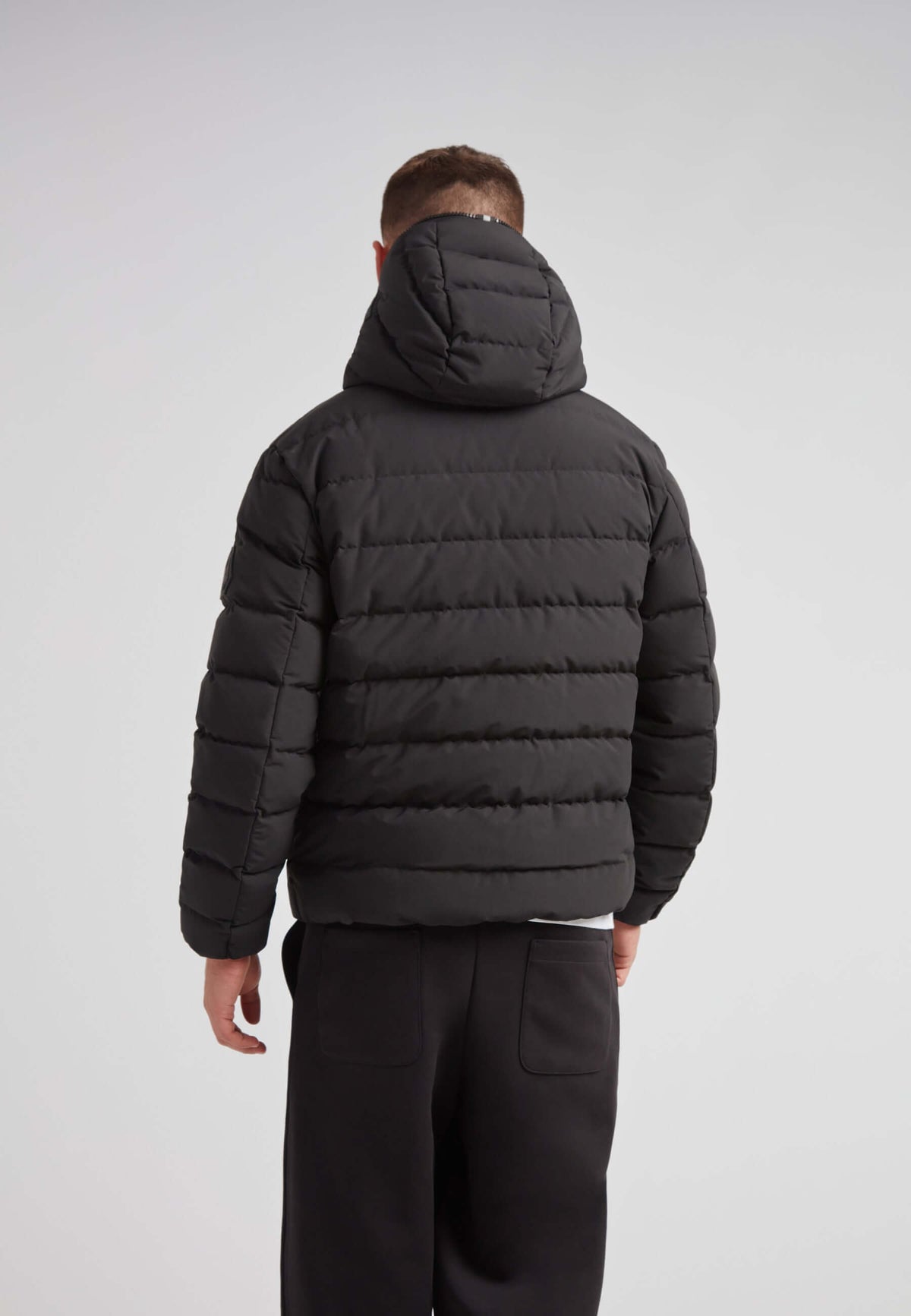 Back view of R4D Tramline Puffer Racer Jacket Matt Black showcasing its puffer design and hood.