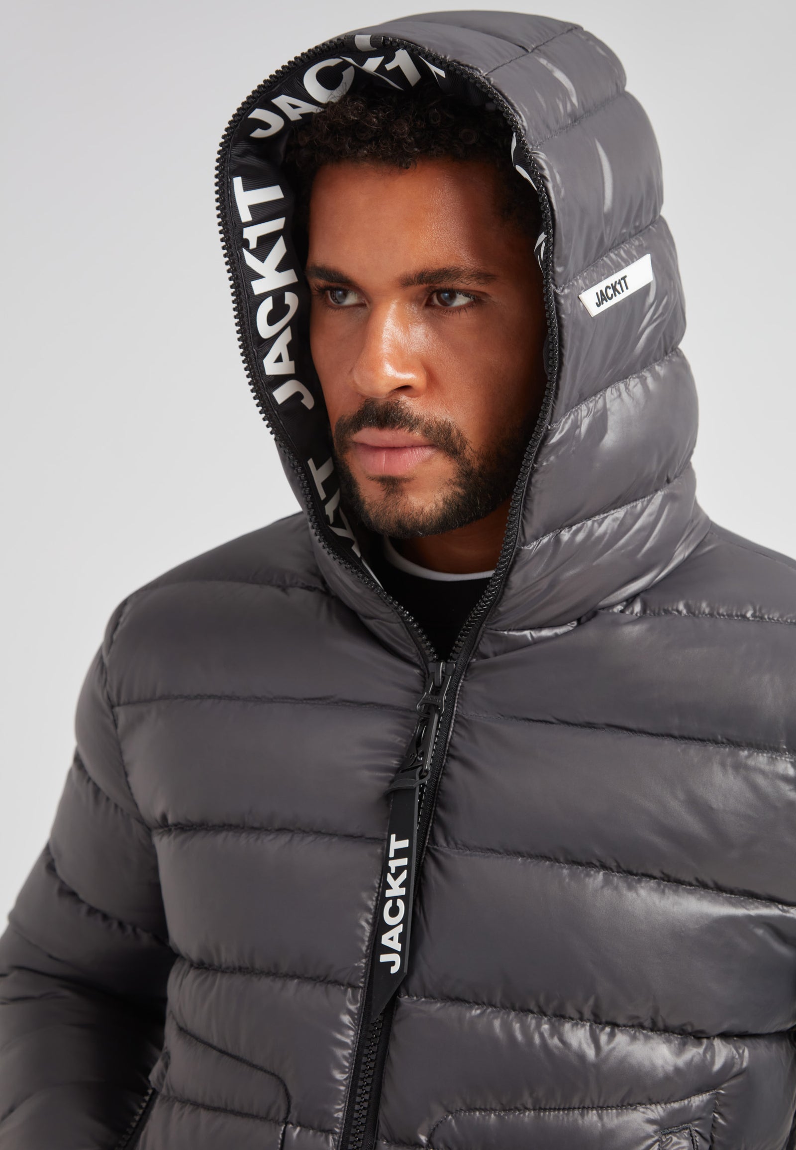 R4D Tramline Puffer Racer Jacket Lux Graphite on model with hood up, showcasing sleek design and performance materials.