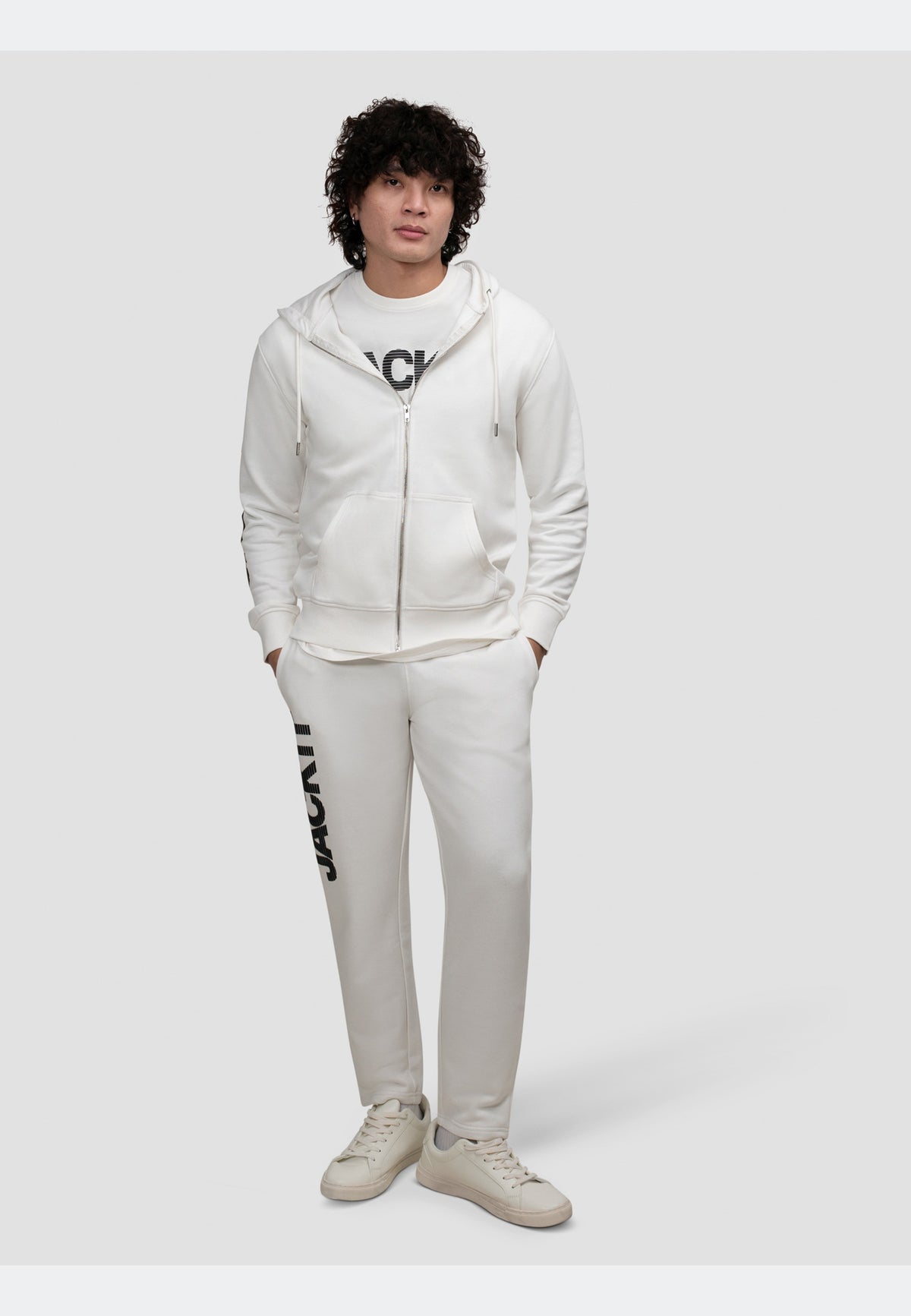 Model wearing off white zip-through hoodie with matching sweatpants, showcasing a relaxed streetwear style.
