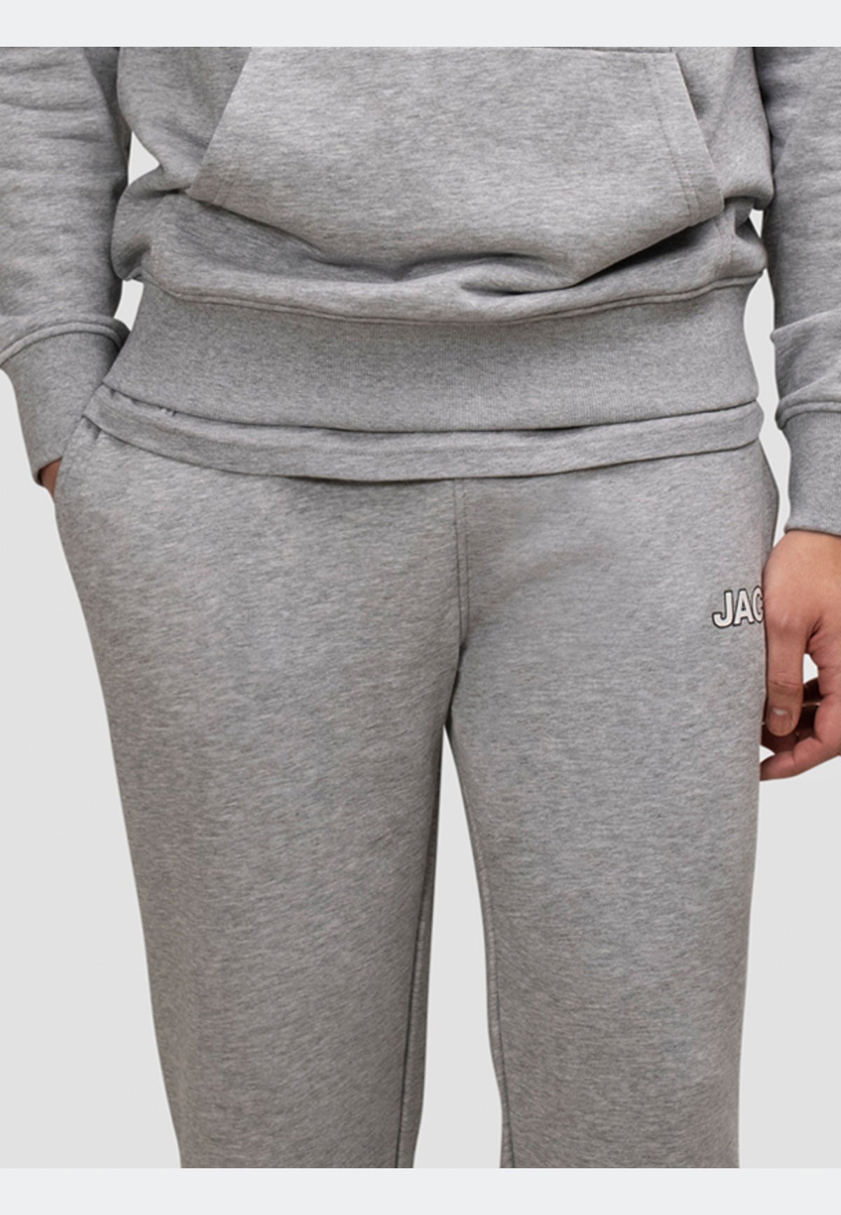 A model wears mid grey heather grey joggers featuring an elasticated waistband and side pockets.