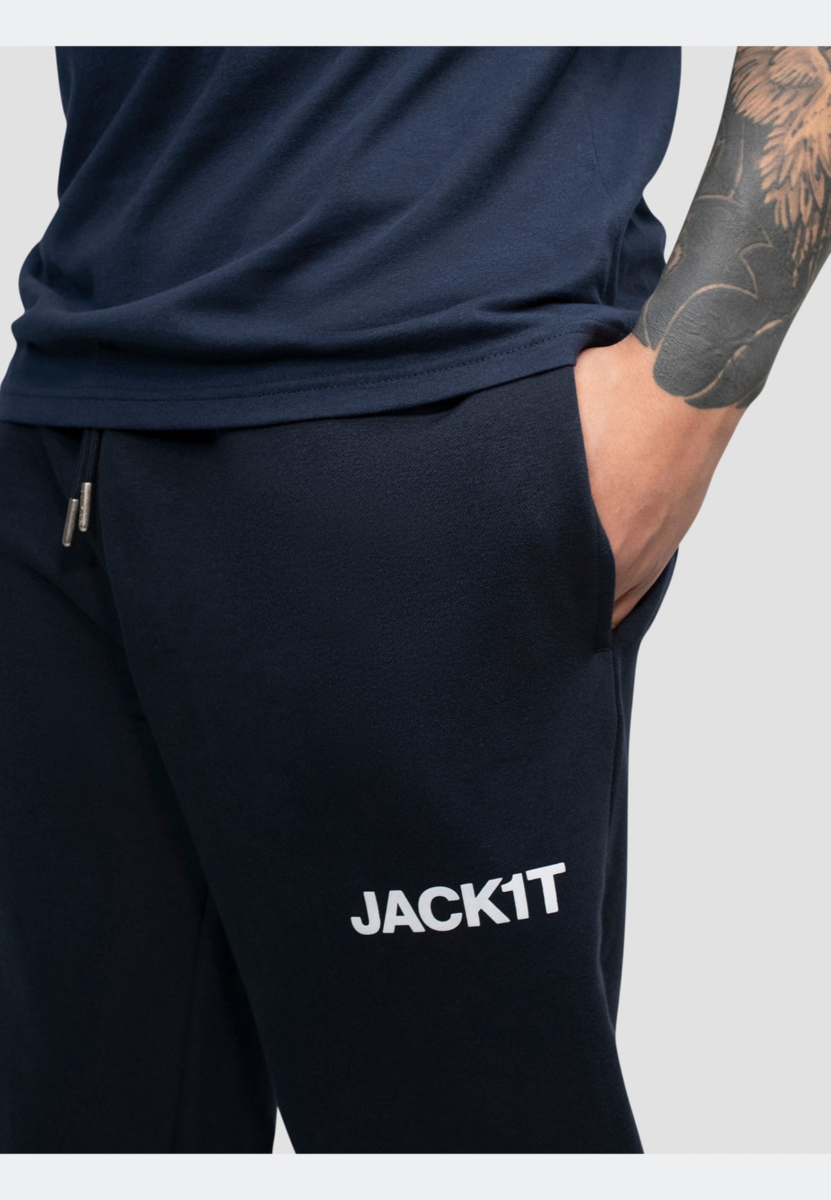 Close-up of navy joggers featuring elasticated waistband and side pockets with branded logo.