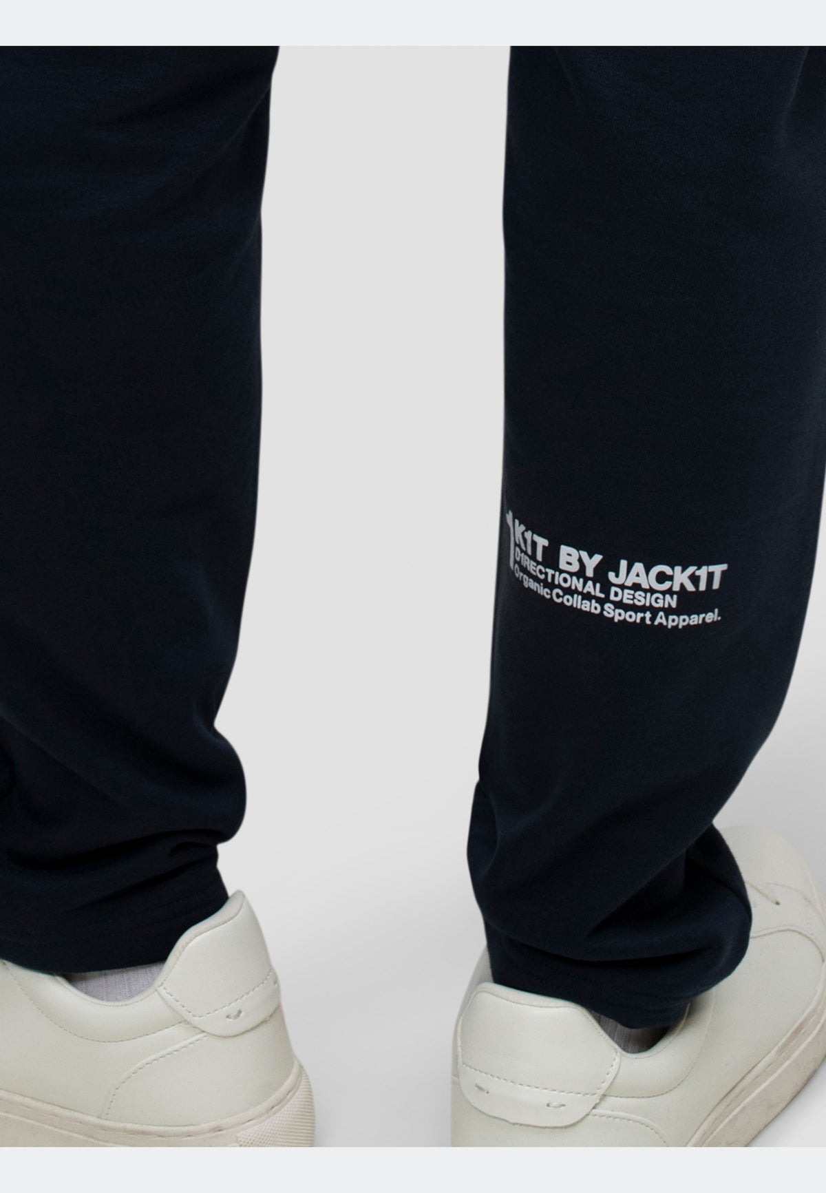 Image of navy joggers featuring an elasticated waistband and subtle branding on the leg, paired with white sneakers.