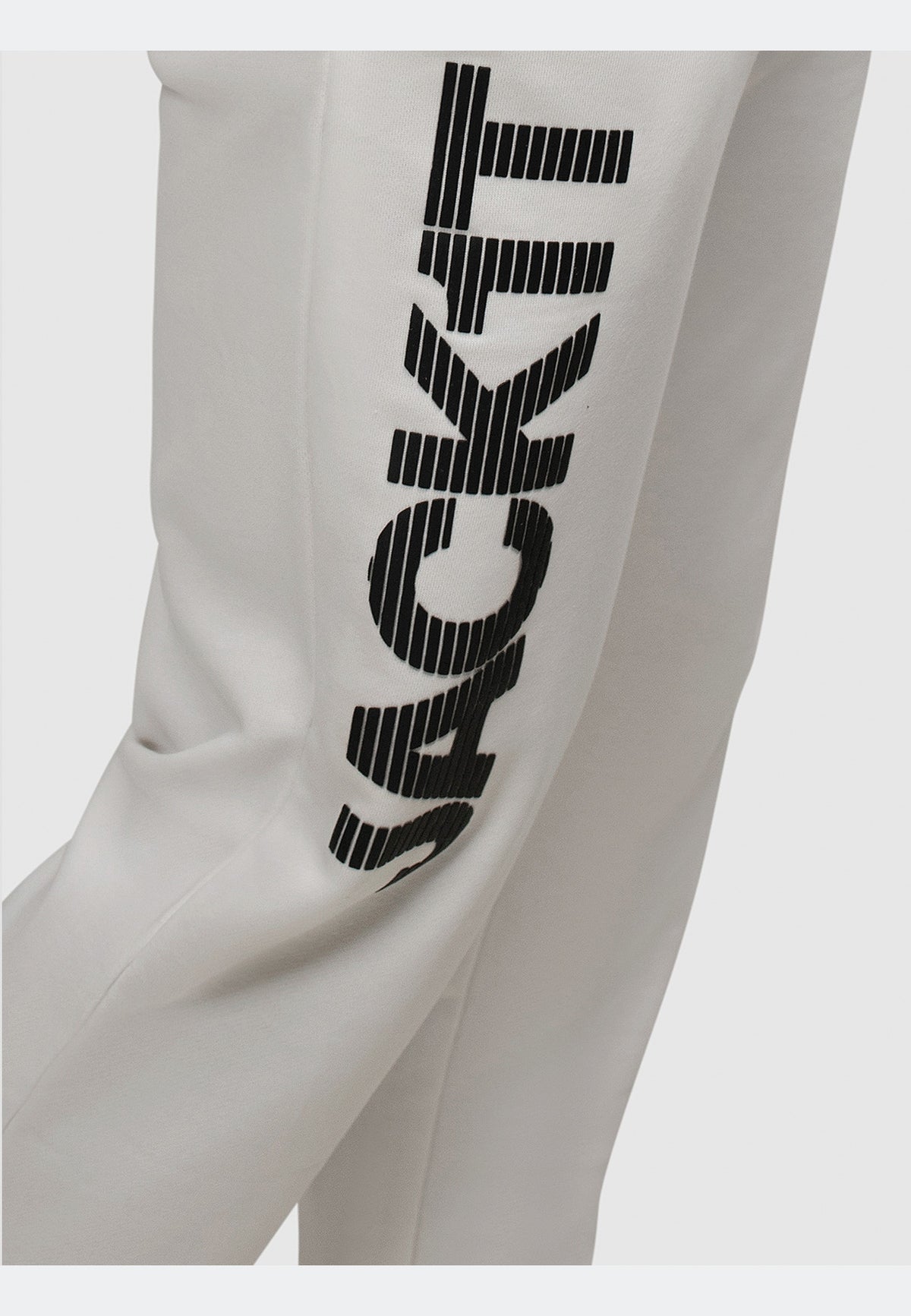 Close-up of off white joggers featuring bold black JACKIT logo on the side for stylish everyday wear.