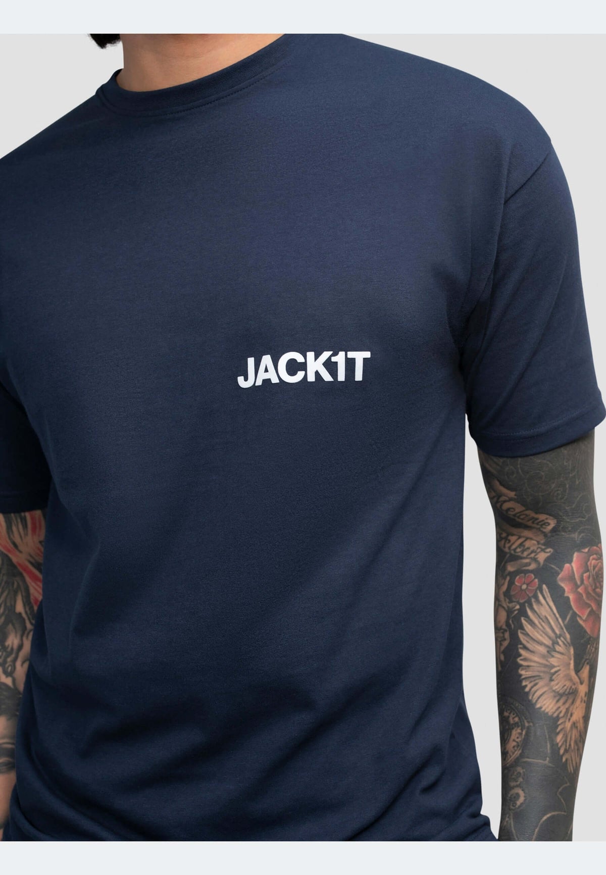 Men's navy t-shirt with white JACK1T logo on chest, showcasing short sleeves and tattoos on arms.