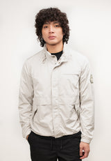 Mens lightweight stone windbreaker modeled by a man with curly hair, showcasing its stylish design and features.