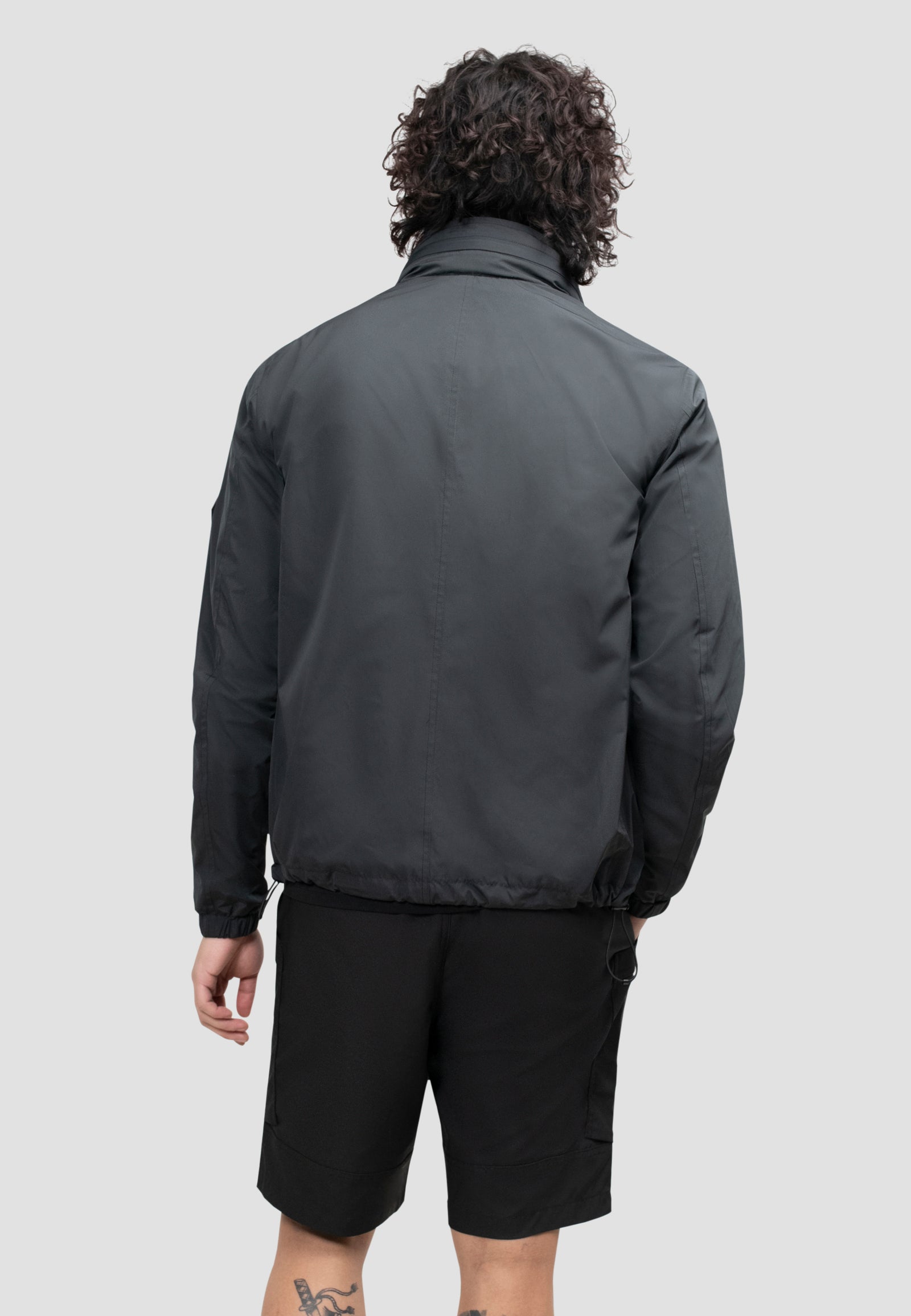 Back view of a model wearing a men's black windbreaker, showcasing its lightweight and functional design.