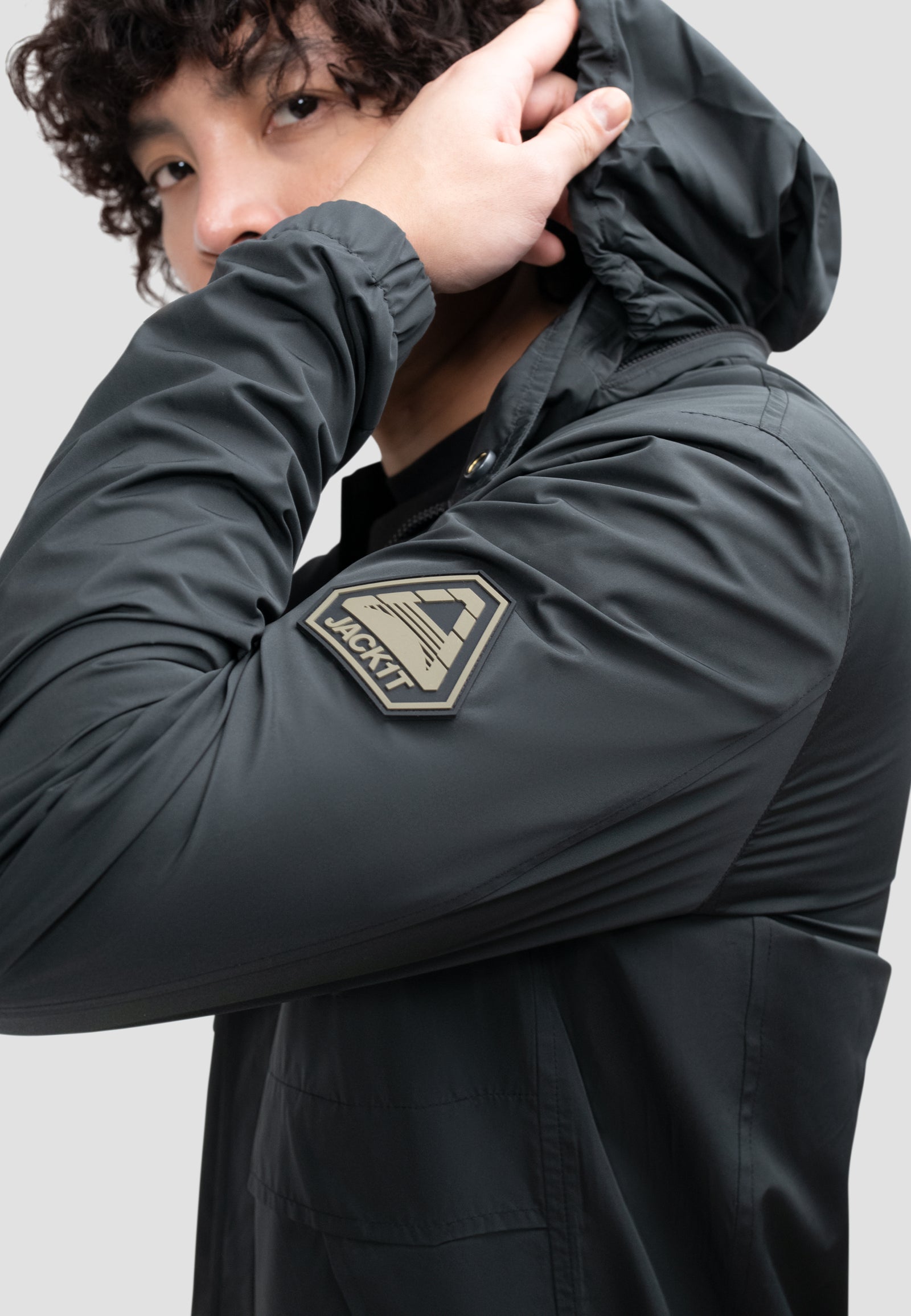 Close-up of a man wearing a men's black windbreaker, showcasing the hood and logo detail.