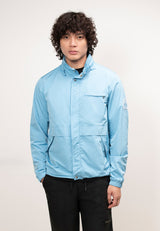Model wearing an Atlas Lightweight Windbreaker in sky blue, showcasing a men's blue windbreaker designed for spring and summer weather.