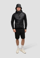 Stylish man wearing a Mens Hybrid Black Hooded Jacket with shorts and bucket hat, showcasing a modern athletic look.