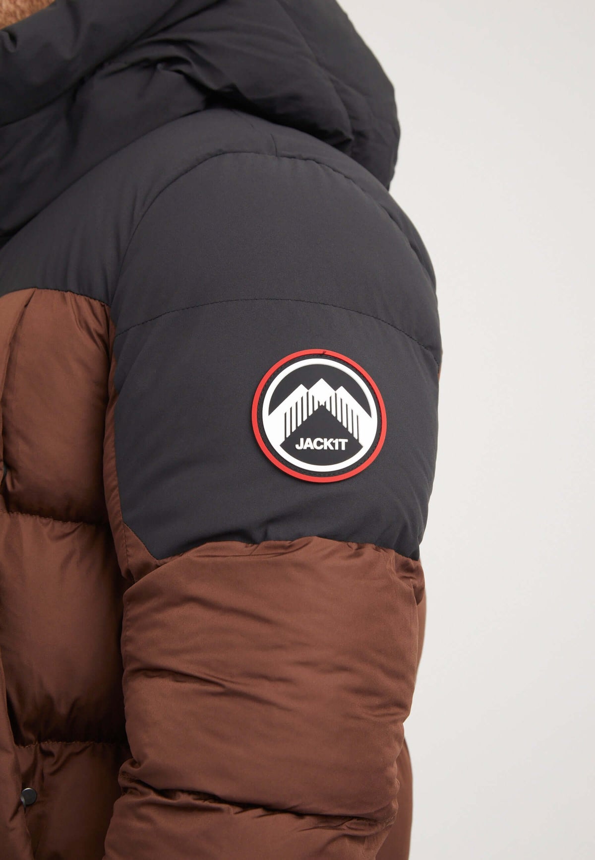 Mens brown puffer jacket featuring a logo patch on the arm, showcasing a durable design and stylish color combination.