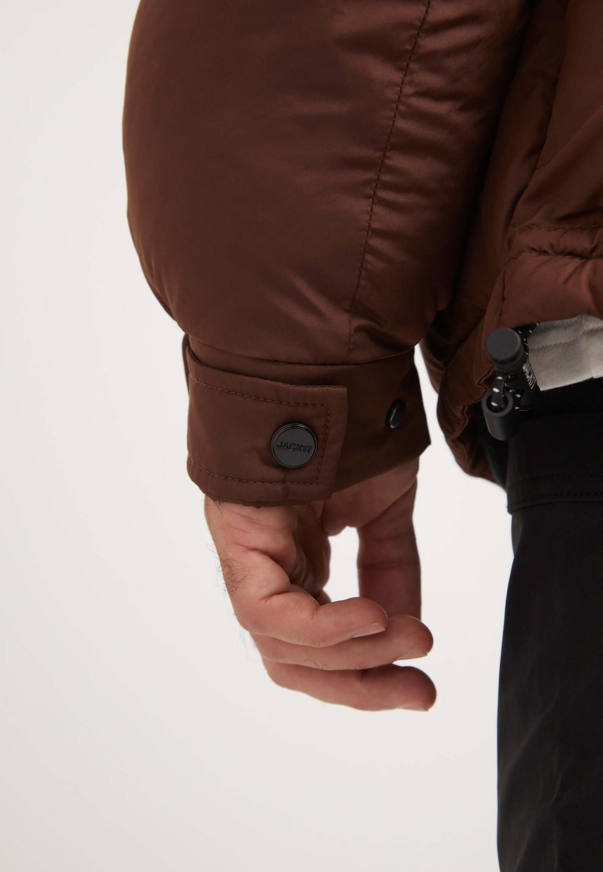Mens brown puffer jacket close-up detailing of cuff showing the premium synthetic insulation and button closure.