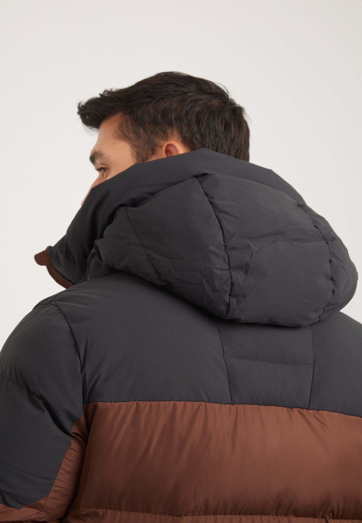 Stylish back view of a model wearing the Mens brown puffer jacket, showcasing the gown-on hood and puffer design.