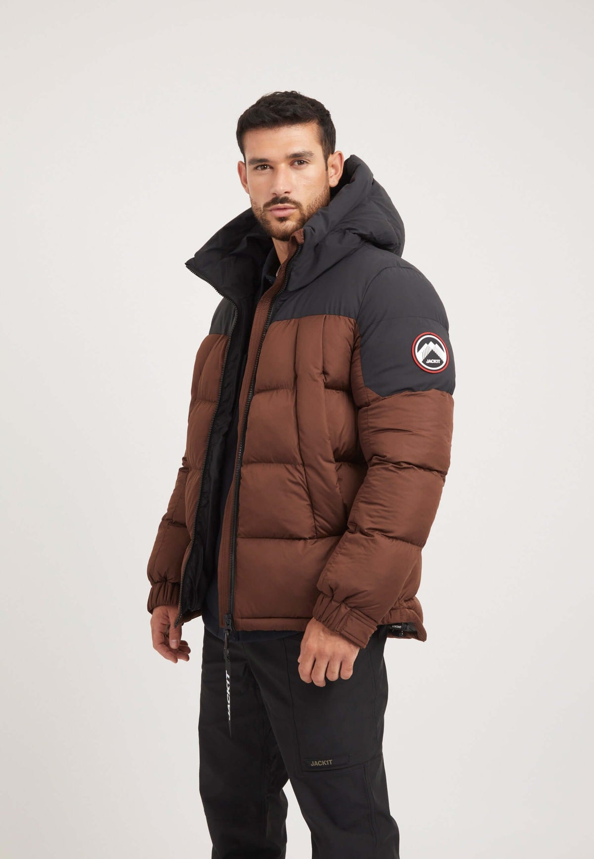 Model wearing a Luna Puffer Jacket in mid brown and black, showcasing a stylish mens brown puffer jacket.