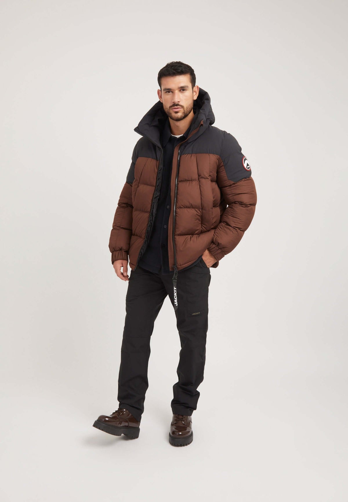 Stylish man wearing a mens brown puffer jacket, showcasing premium insulation and modern design, perfect for cold weather.