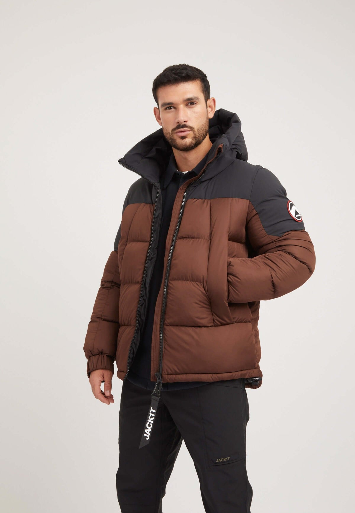 Model wearing the Luna Puffer Jacket in mid brown and black, showcasing the mens brown puffer jacket design.