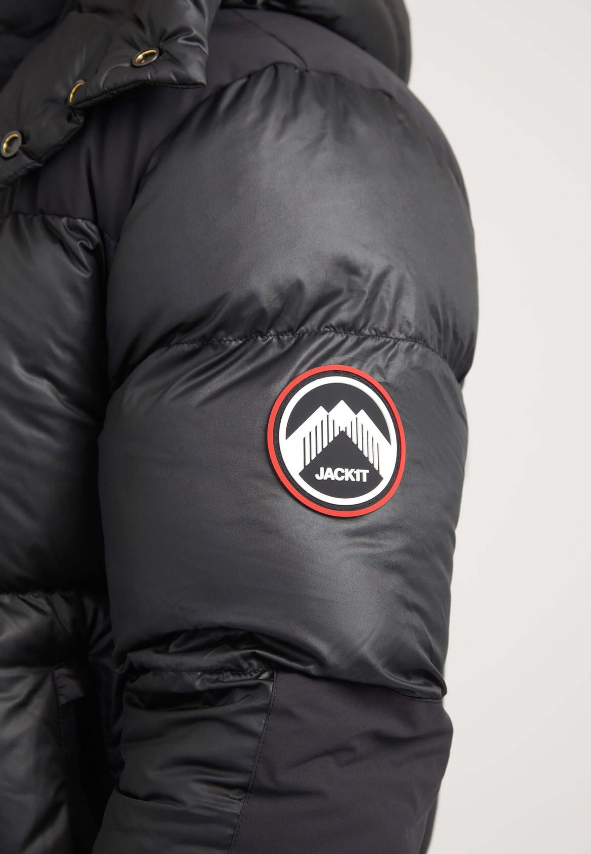 Close-up of the sleeve logo on a mens black parka featuring the JACKIT brand emblem.