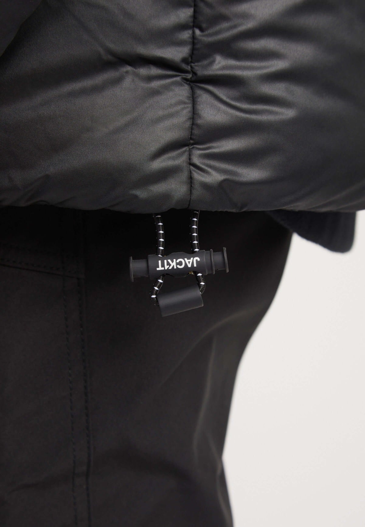 Close-up of the adjustable drawstring detail on the hem of a mens black parka, featuring premium insulation and sleek design.