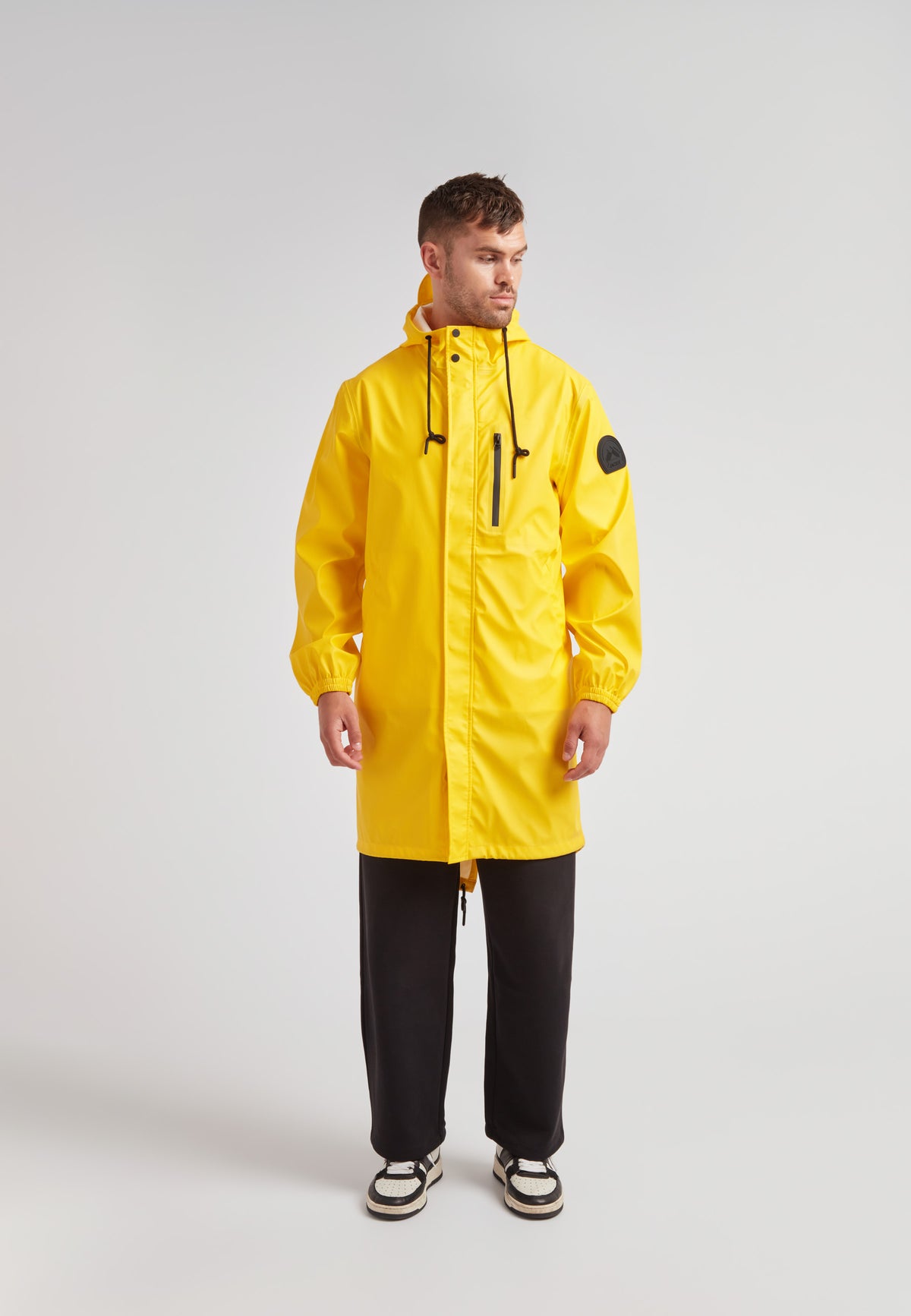 Model showcasing a yellow unisex long raincoat from ELEMENTS collection, designed for lightweight comfort and style.